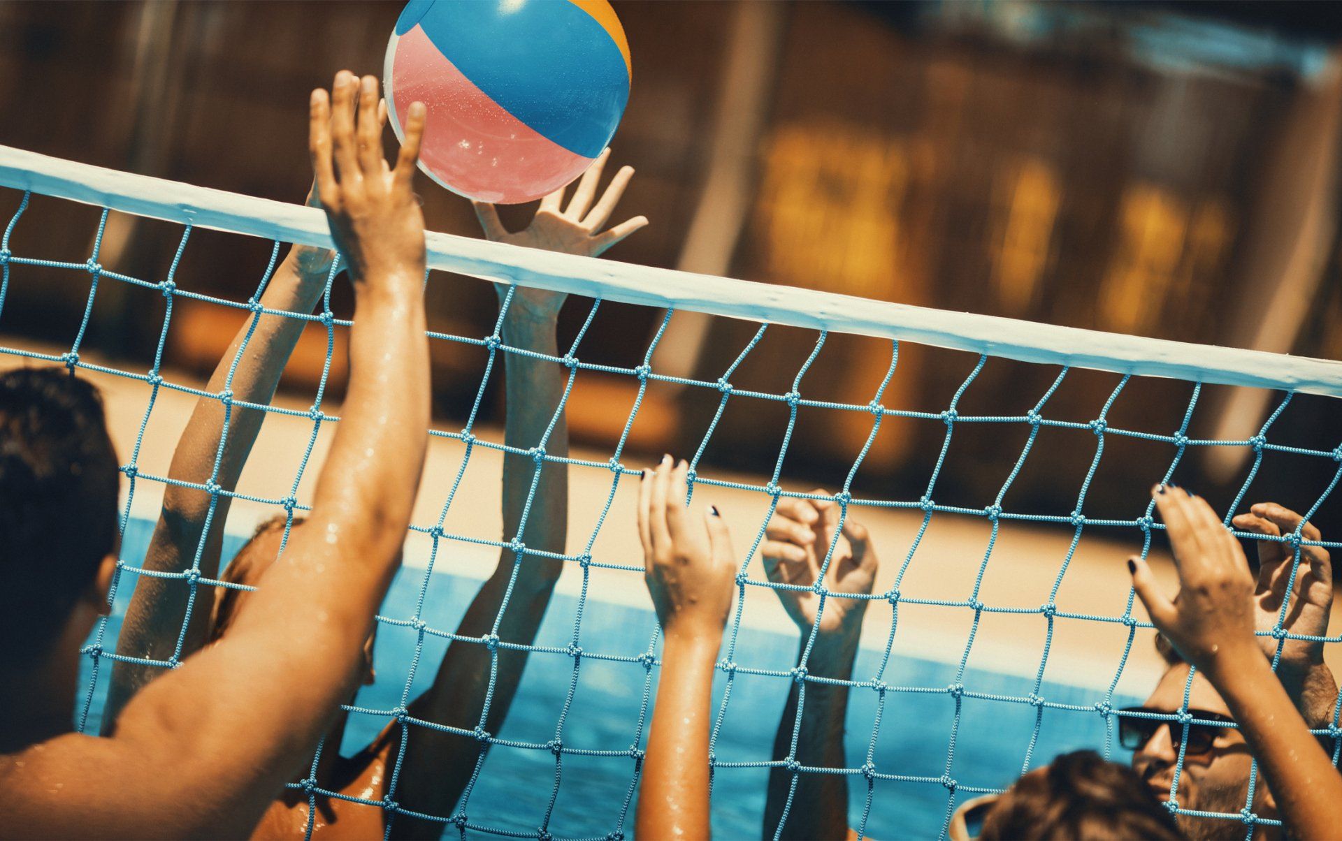 A group of people are playing volleyball in a pool.