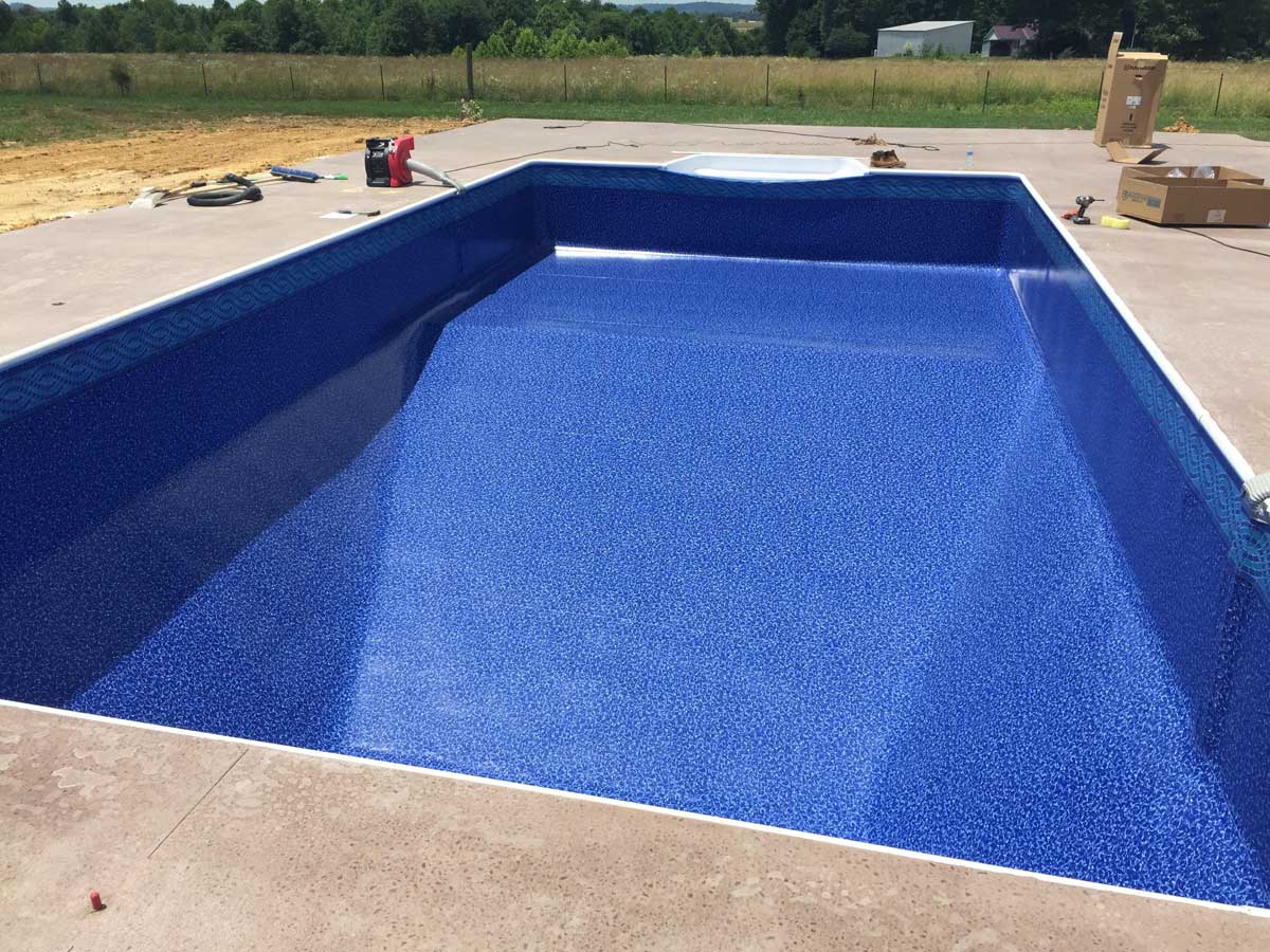 A large blue swimming pool is being built in a backyard.