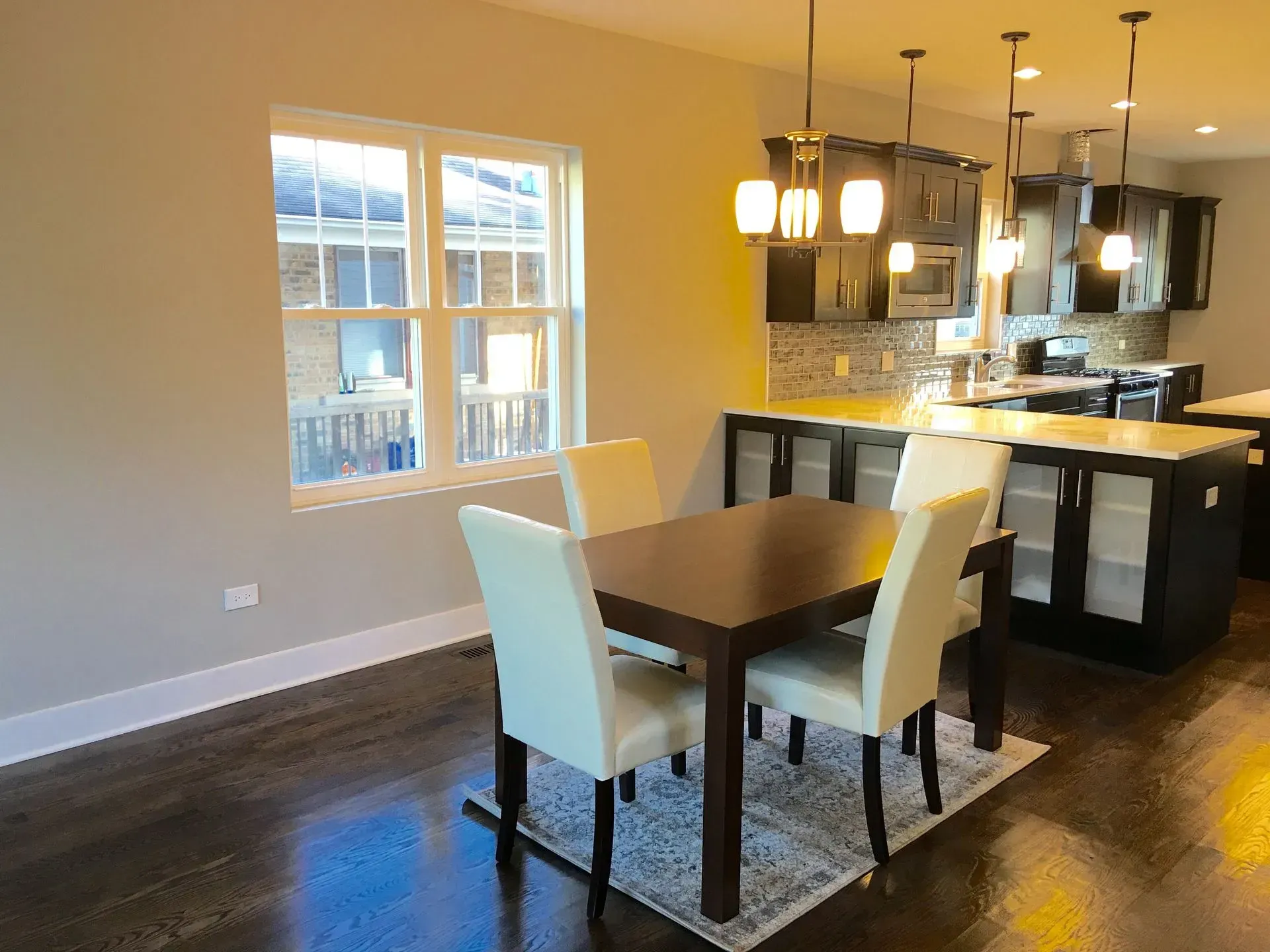 A dining room with a table and chairs and a kitchen in the background