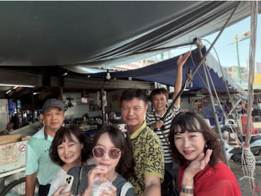 六個人在水邊的樹蔭下，帶著笑容地舉杯慶祝。