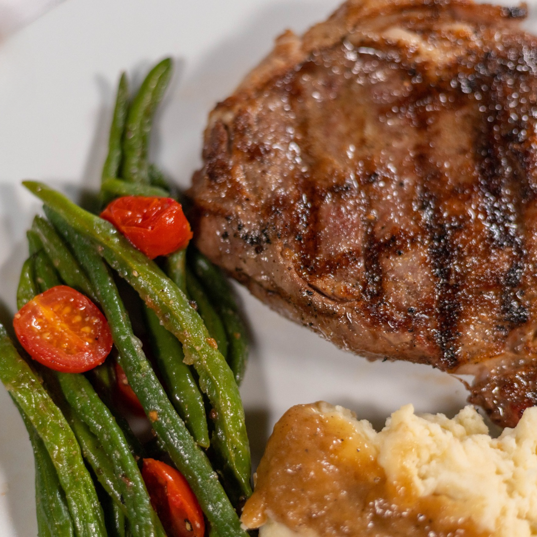 A plate of food with green beans tomatoes and mashed potatoes