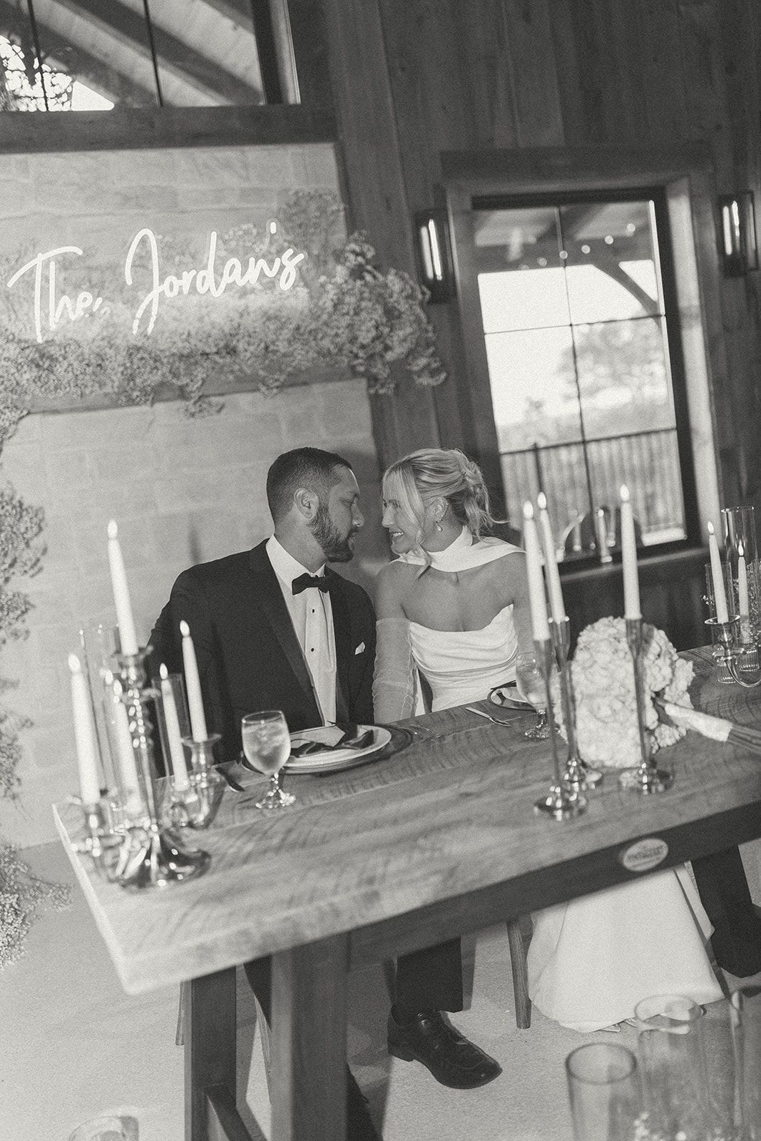 Couple seated at a decorated dinner table with candles in a dimly lit room.