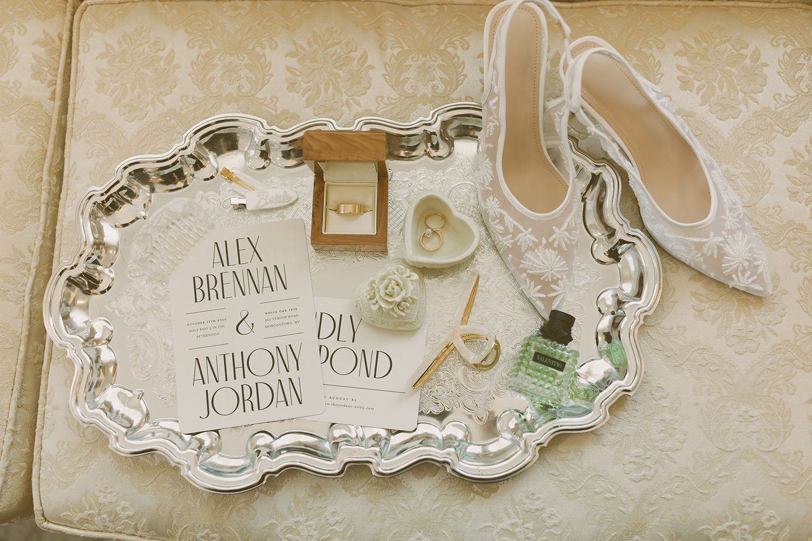Tray with wedding accessories: pearl necklace, rings, perfume bottle, shoes, and handwritten note.