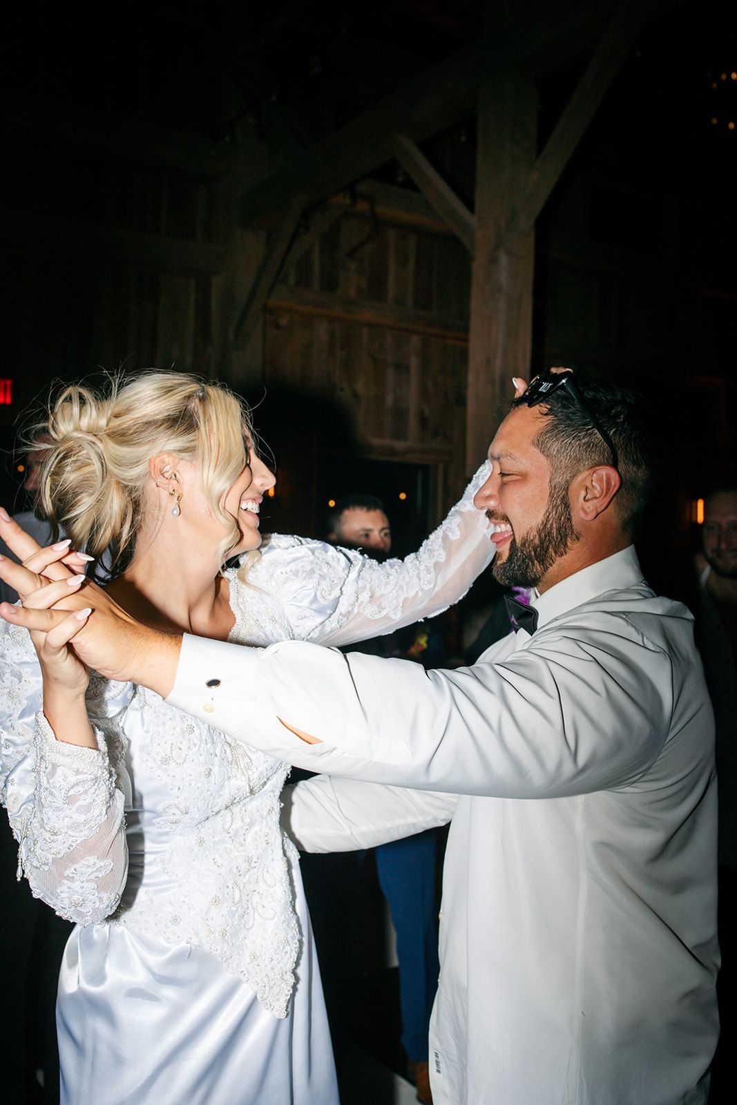 Couple dancing closely at a nighttime celebration, smiling and holding each other in white clothing.