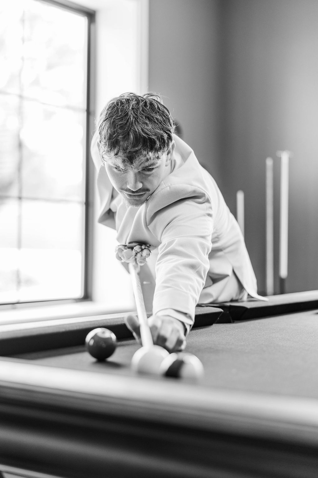 Person lining up a shot at a pool table in a black-and-white scene