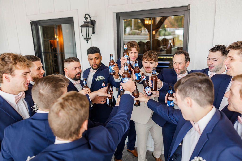 Group of men in blue suits and white shirts toasting drinks indoors at a celebration