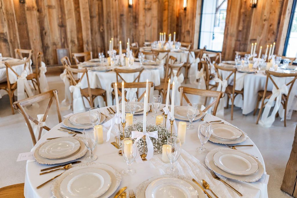 Elegant banquet hall with round tables, white tablecloths, candles, and rustic wooden walls