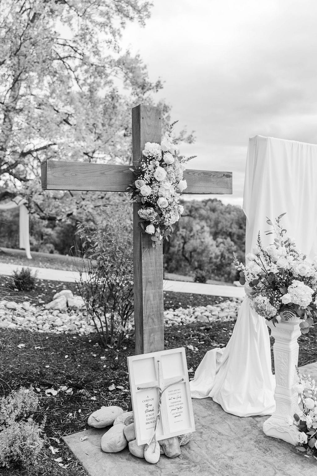 White memorial cross with flowers and candles in a garden setting