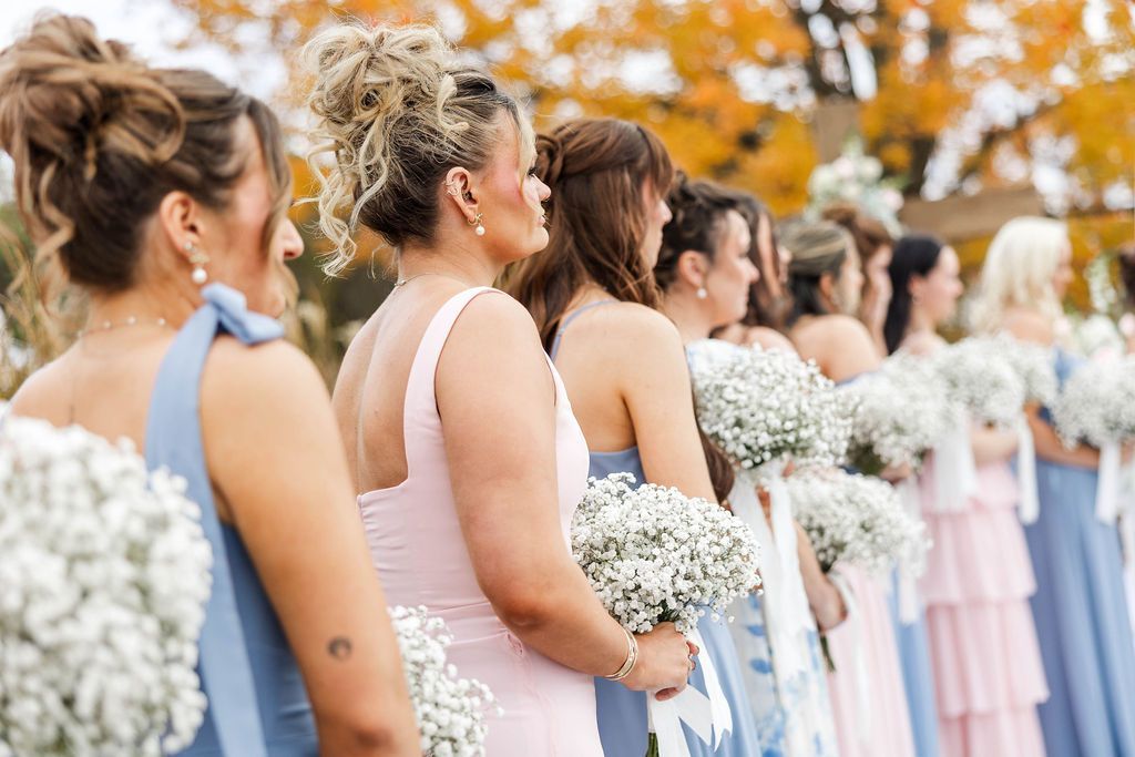 Bridesmaids in pastel dresses holding white bouquets during an outdoor wedding ceremony