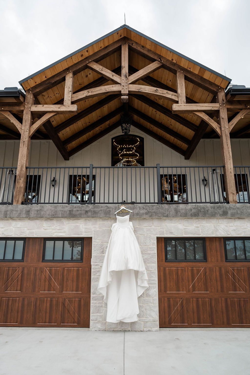 White dress hanging centered on a wooden balcony beneath a peaked timber roof and stone facade