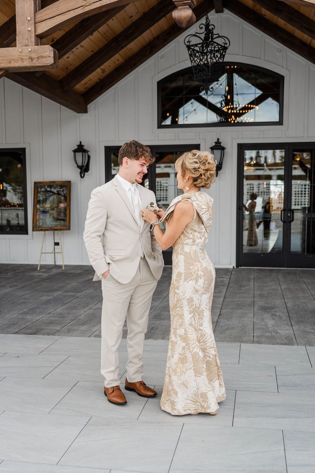 Two people in formal attire standing and holding hands outside a white building entrance