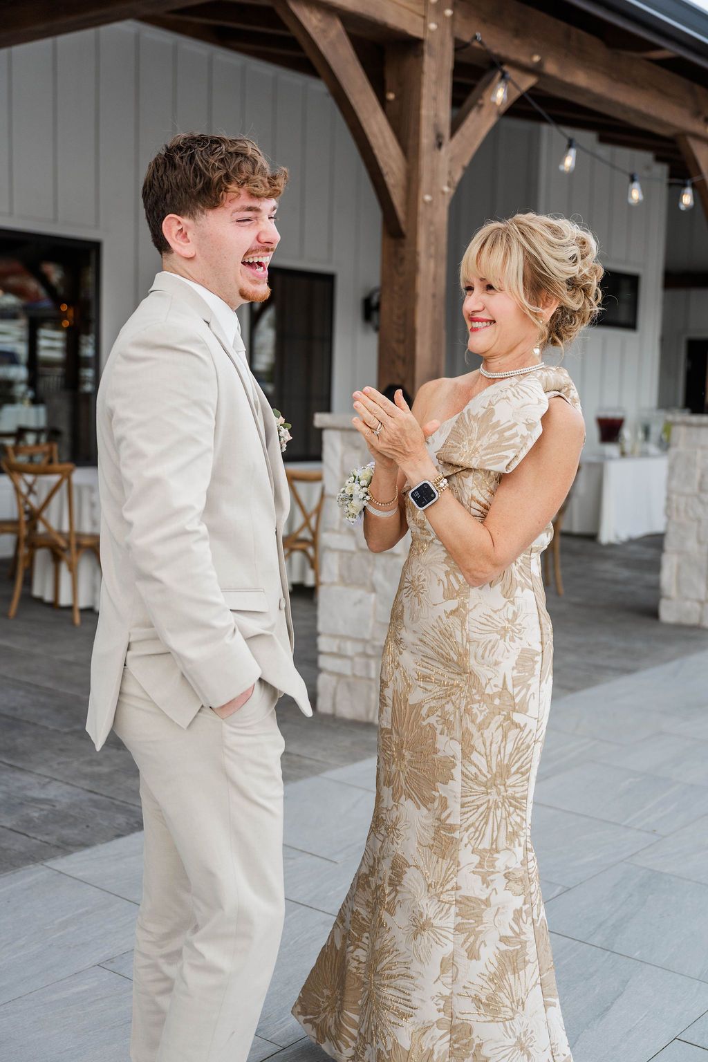 Two people in formal attire smiling outdoors at a wedding venue