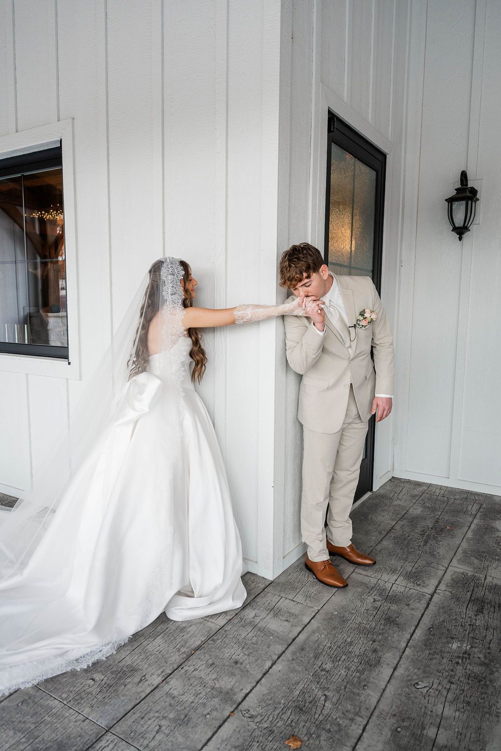 Bride and groom in wedding attire sharing a playful moment on a white porch