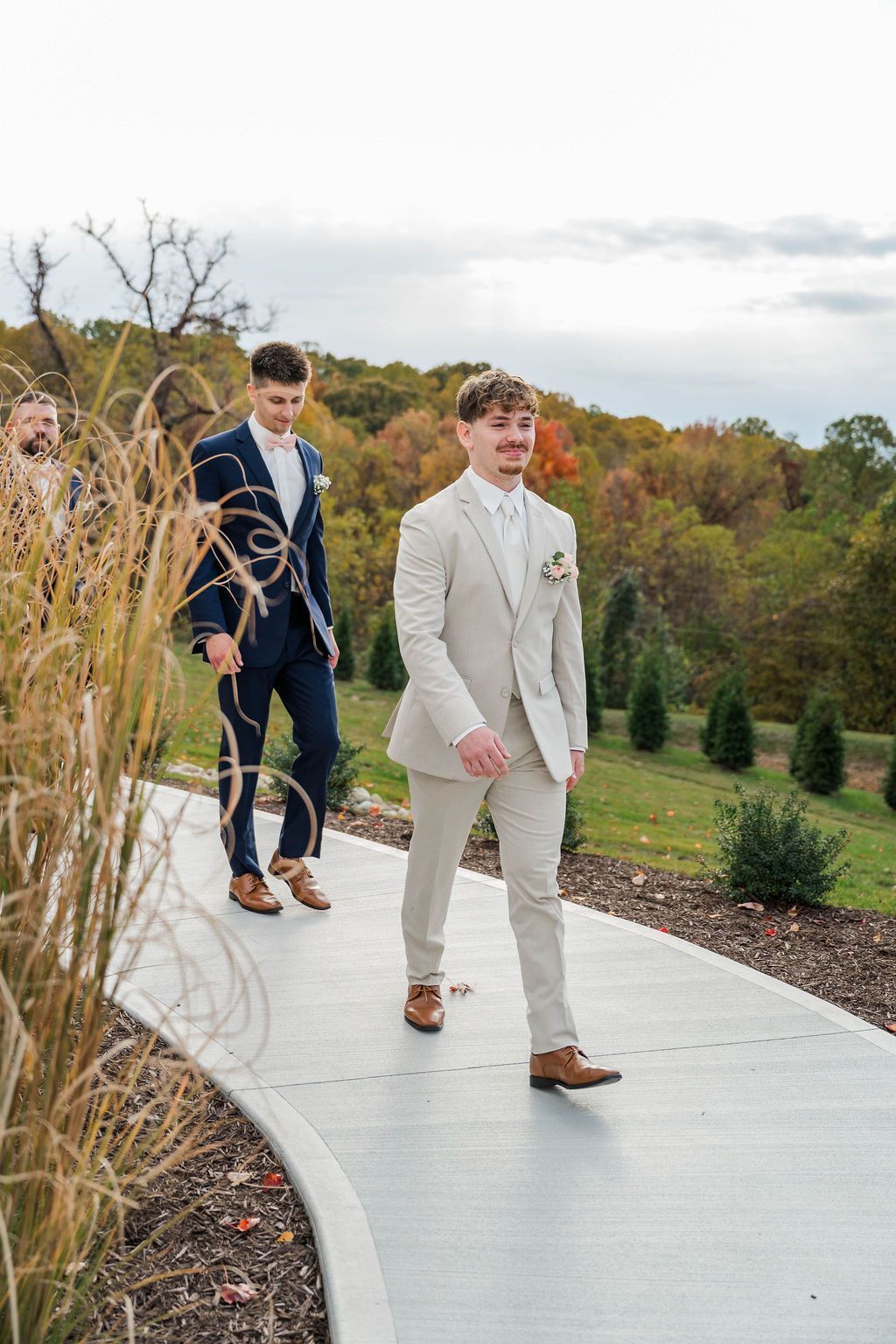 Two men in suits walking along a curved path in a landscaped garden in autumn