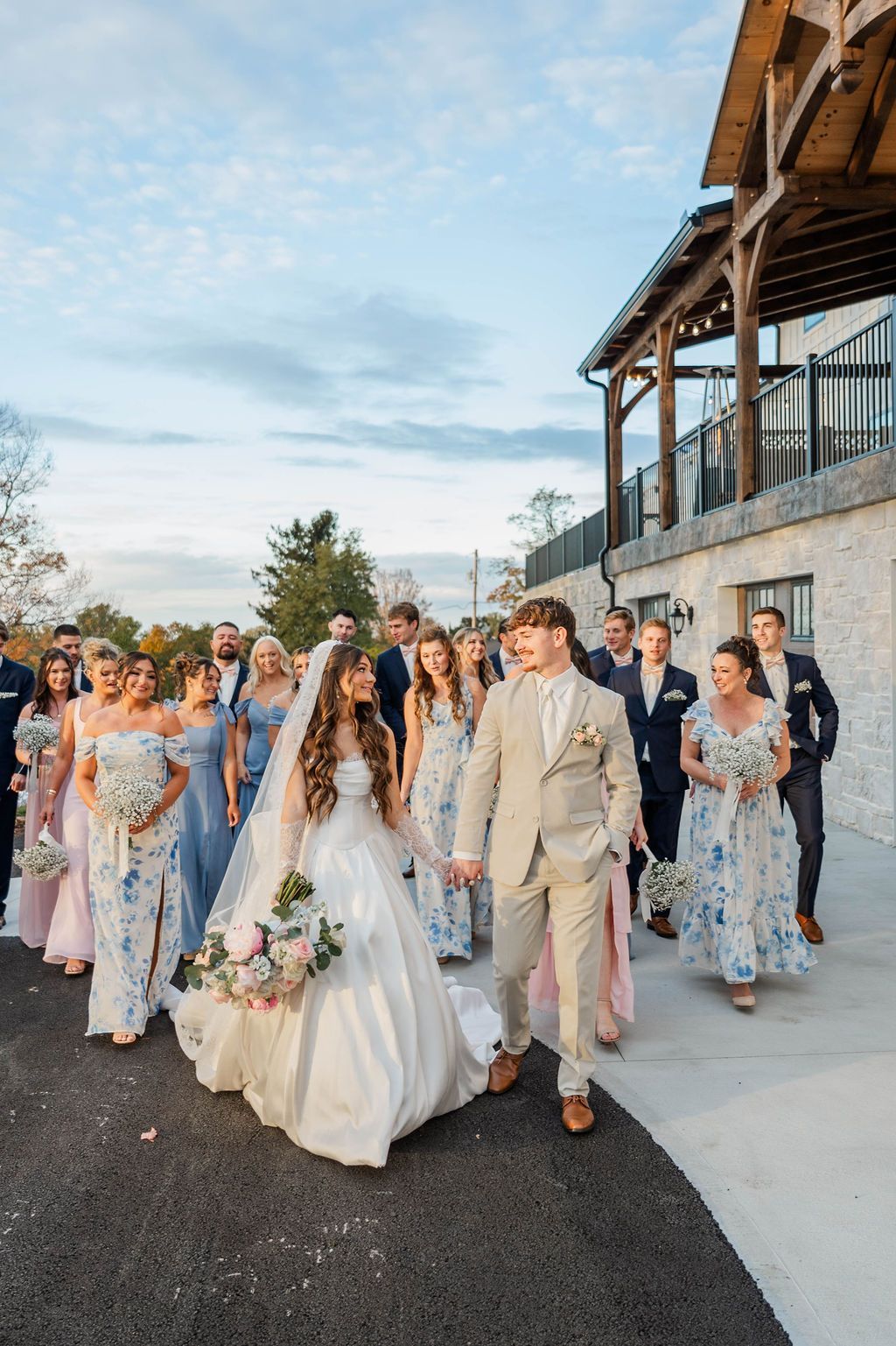 Wedding party walking outdoors beside a stone building at sunset
