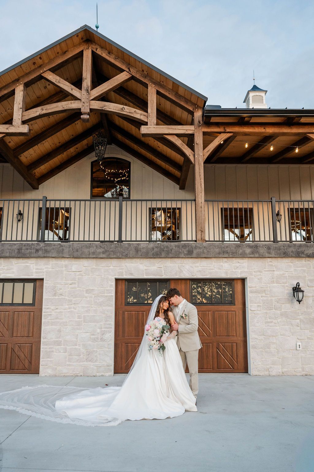 Bride and groom embracing in front of a rustic barn wedding venue