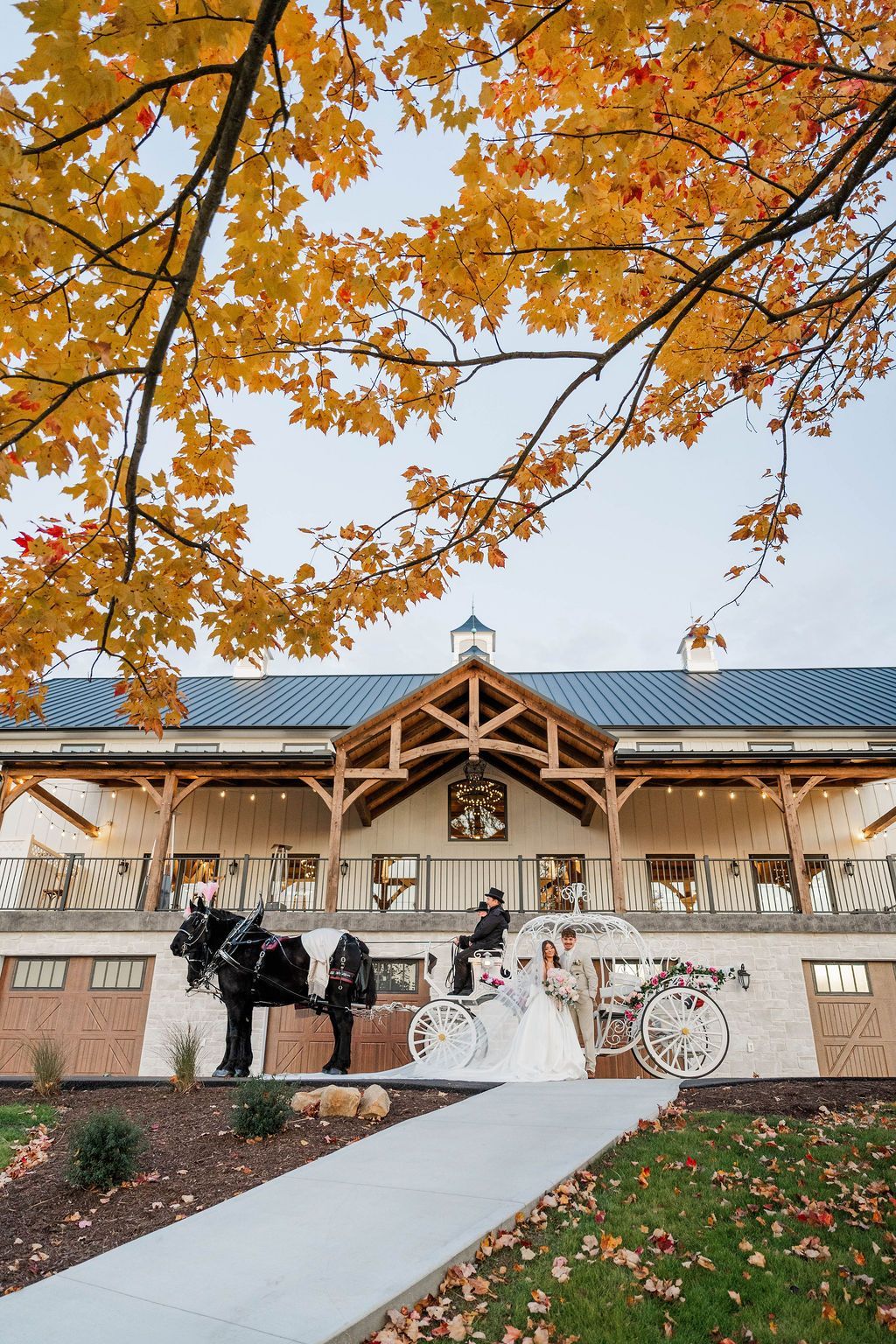 Bride and groom at an outdoor pavilion with autumn leaves overhead