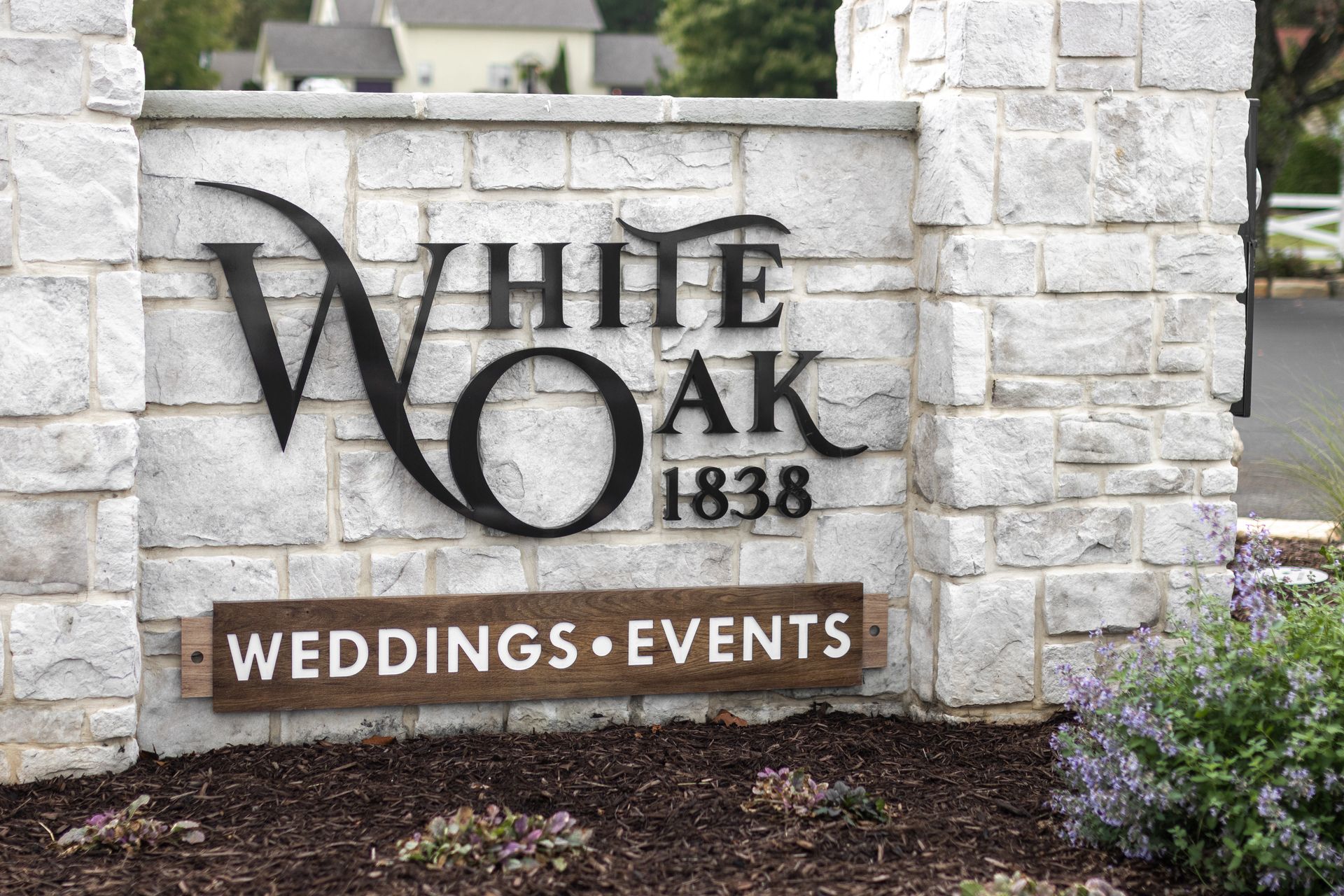 White Oak wedding and events sign on a stone wall with greenery nearby