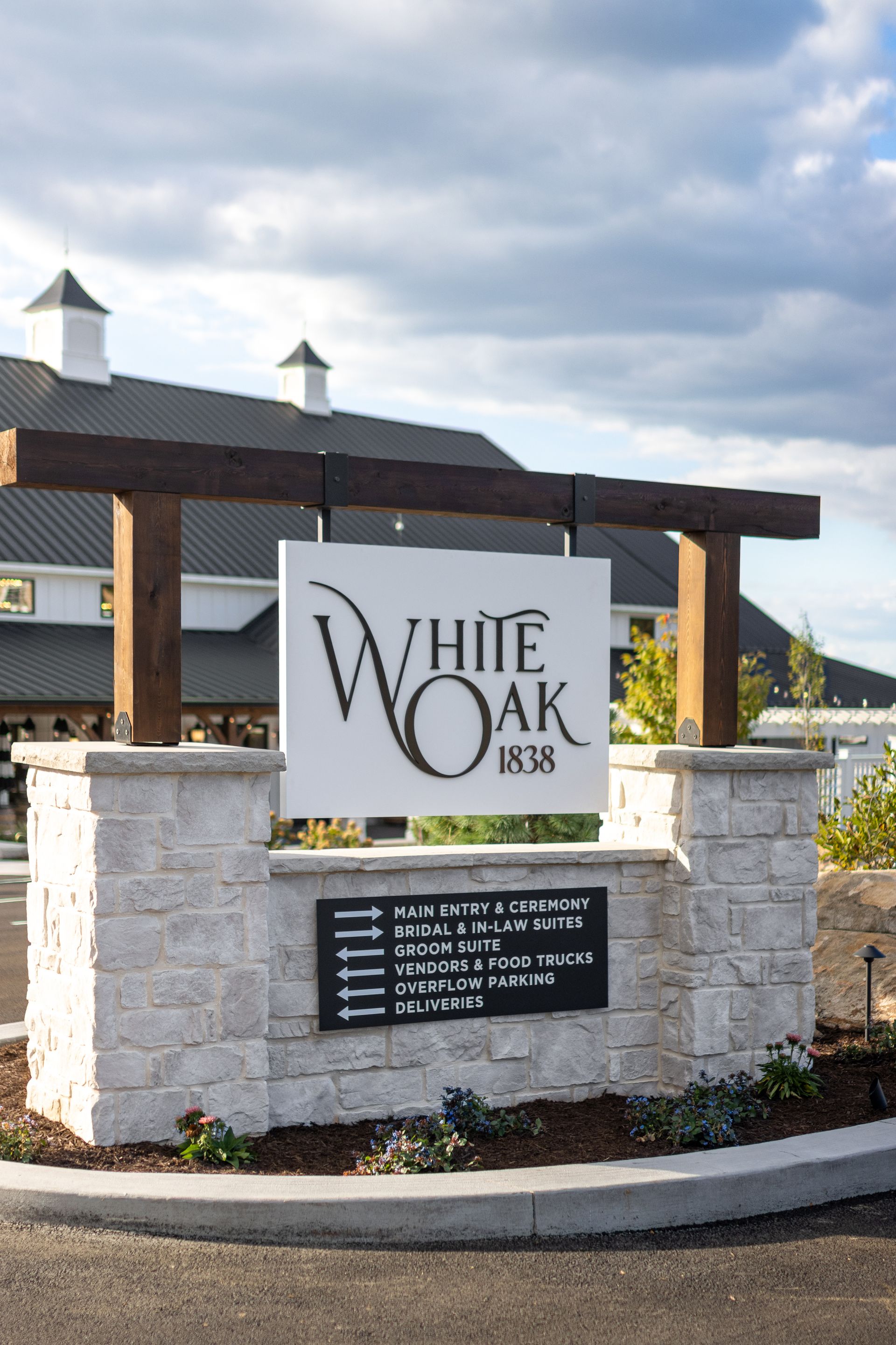 White Oak Inn sign on a stone base beside a roadway under a cloudy sky.