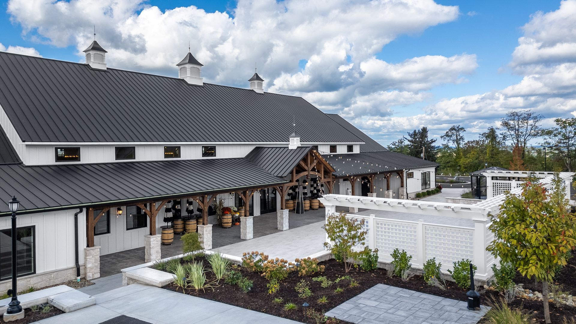 White building with dark roof and landscaped courtyard under a cloudy blue sky