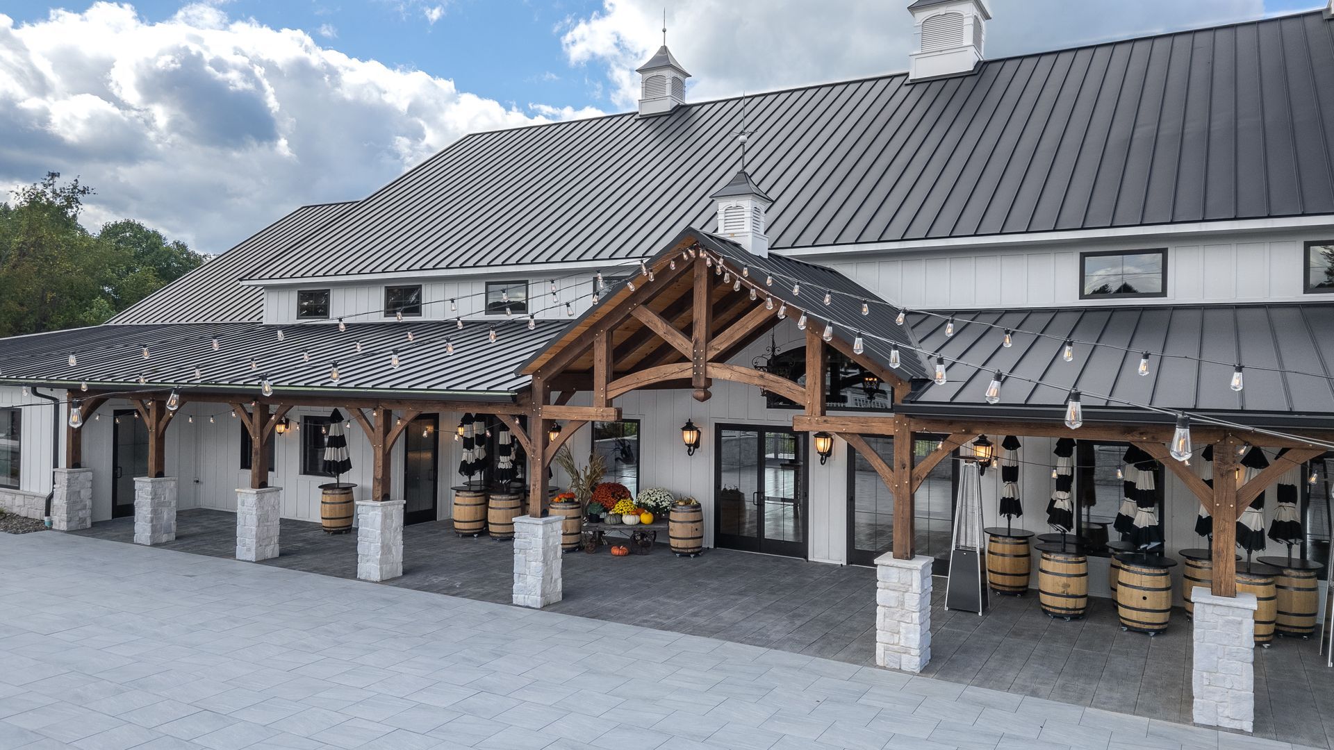 Covered outdoor market with striped roof, wooden beams, and stone columns under a cloudy sky