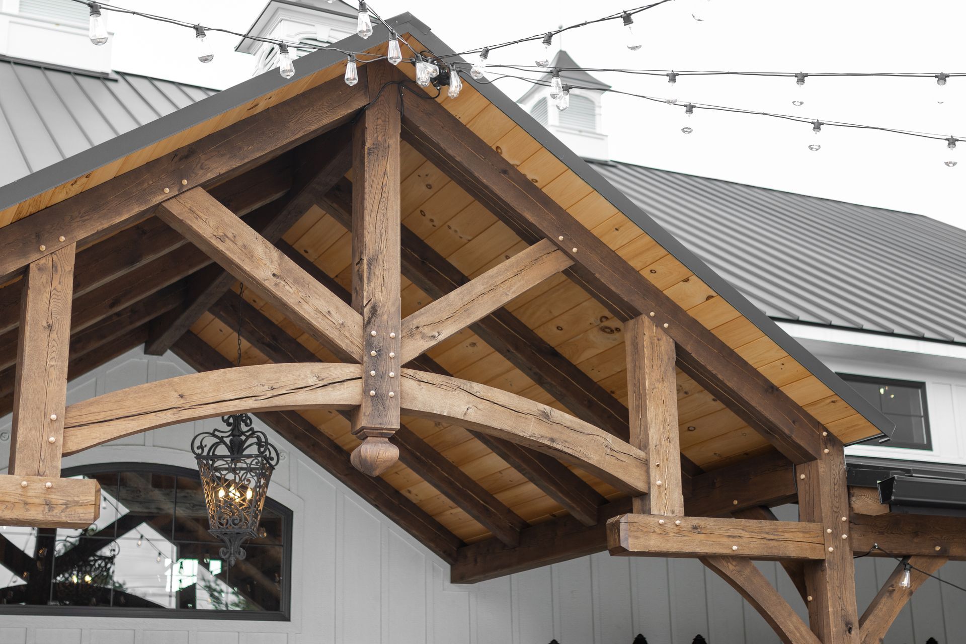 Wooden beam trusses under a sloped roof over a covered outdoor patio