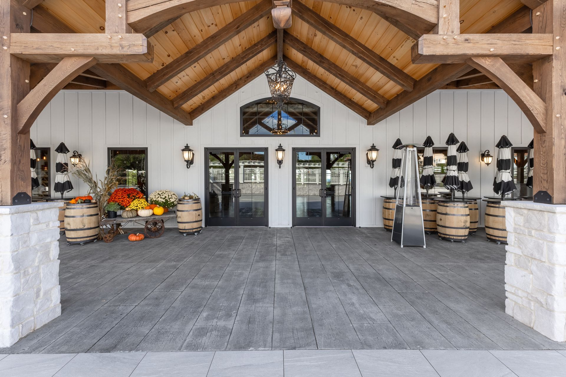 Rustic barn-style entryway with wooden beams, gray floor, and flower displays on both sides