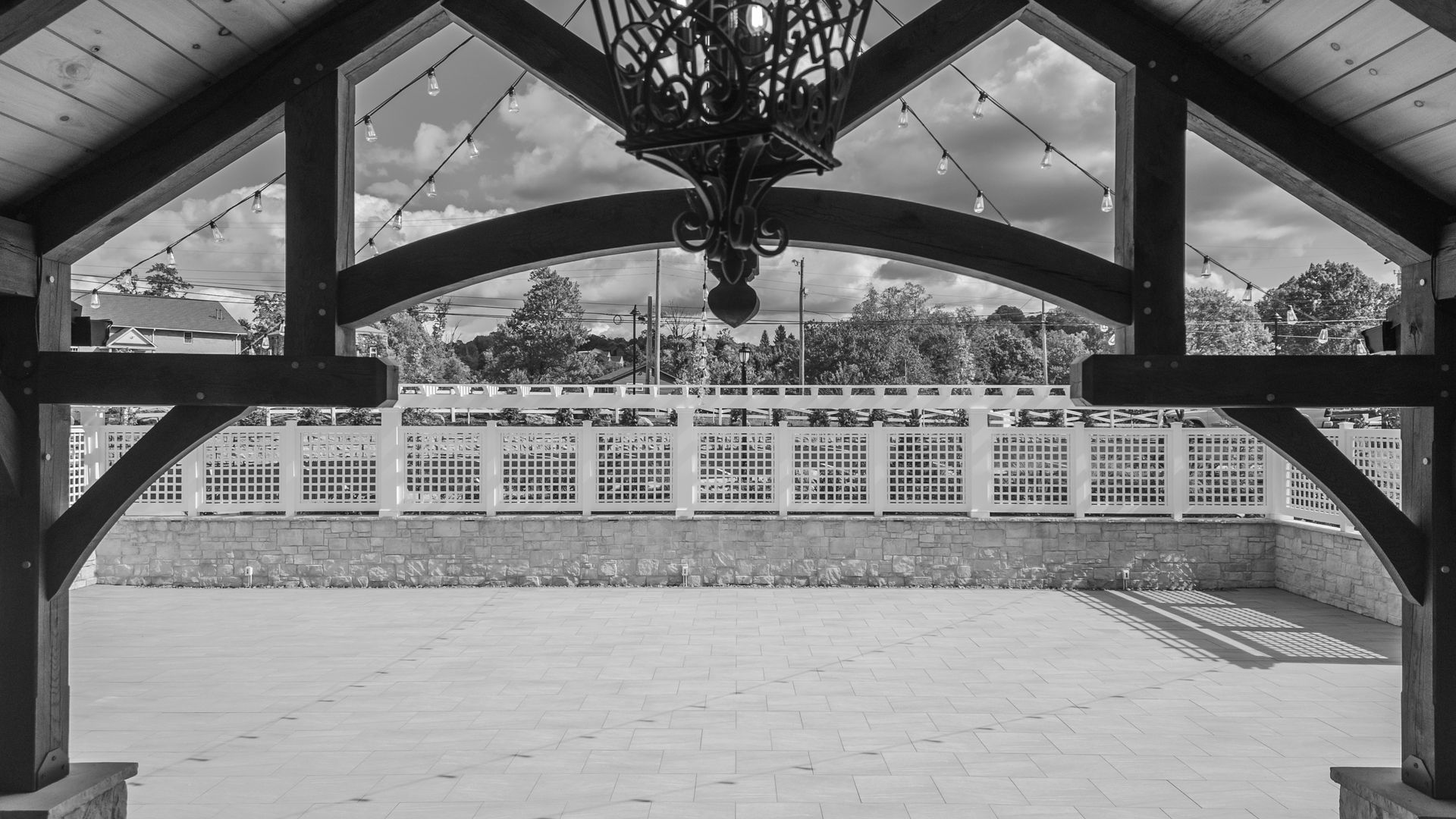Covered pavilion overlooking an open courtyard and white building facade, seen in black and white.