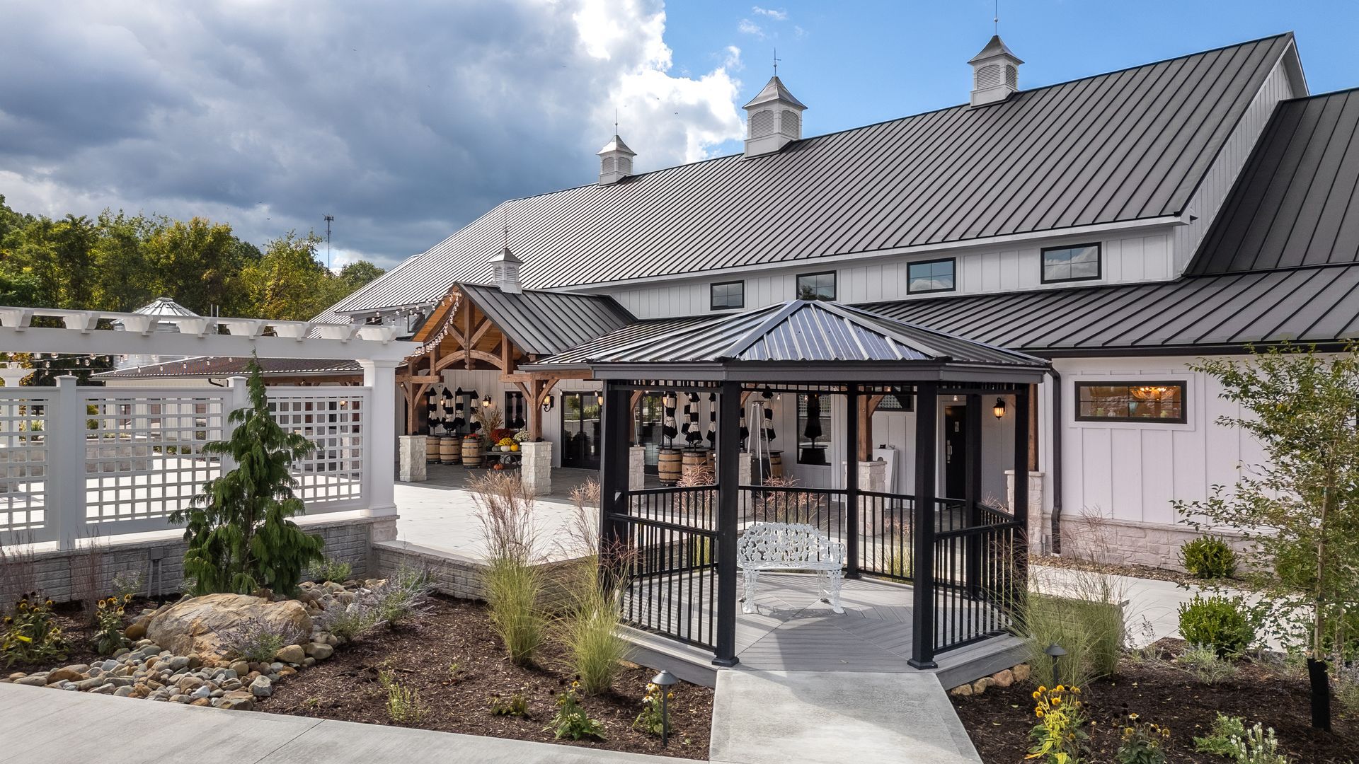 Outdoor patio with black-and-white striped umbrellas beside a white building and garden path