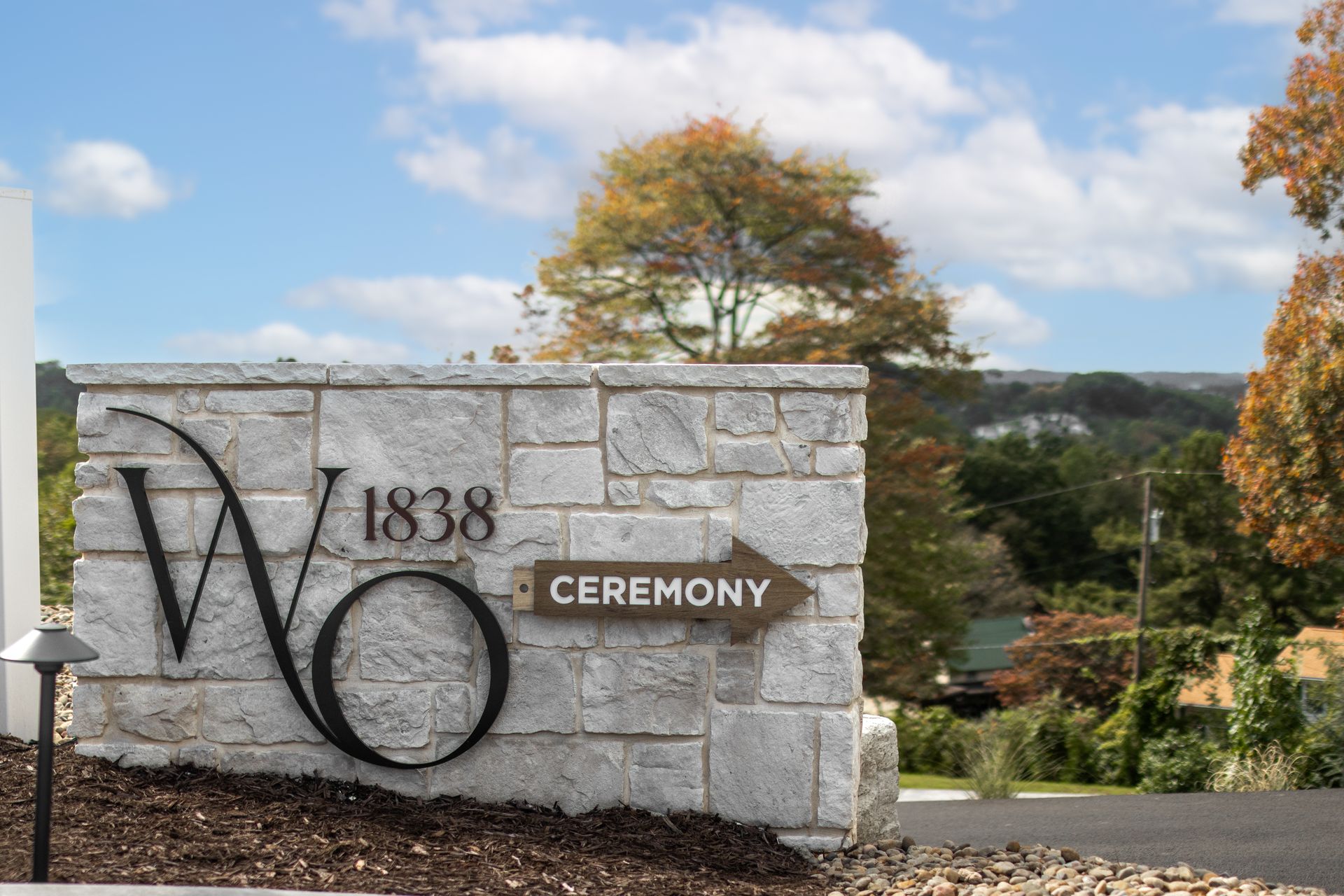 Stone ceremony sign with “W 1538” beside a tree and blue sky overlooking a landscape.
