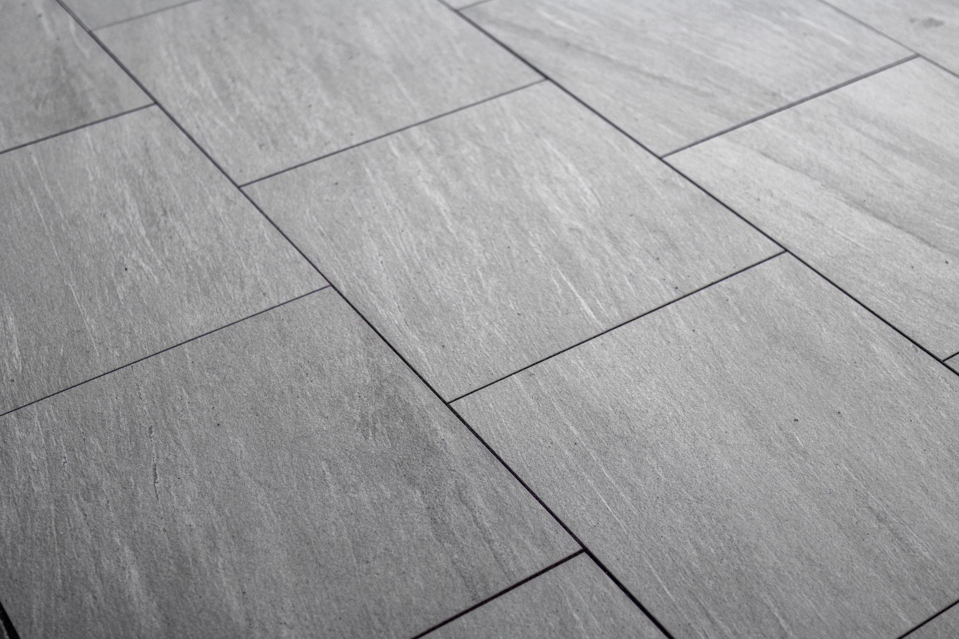 Gray stone pavement with large rectangular tiles and diagonal grout lines