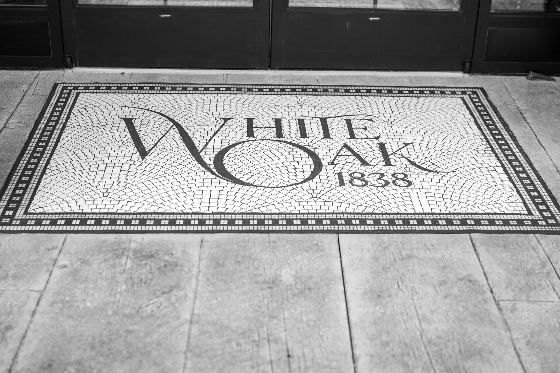 Black-and-white tiled floor with a decorative mosaic reading “White Oak 1838” at an entrance