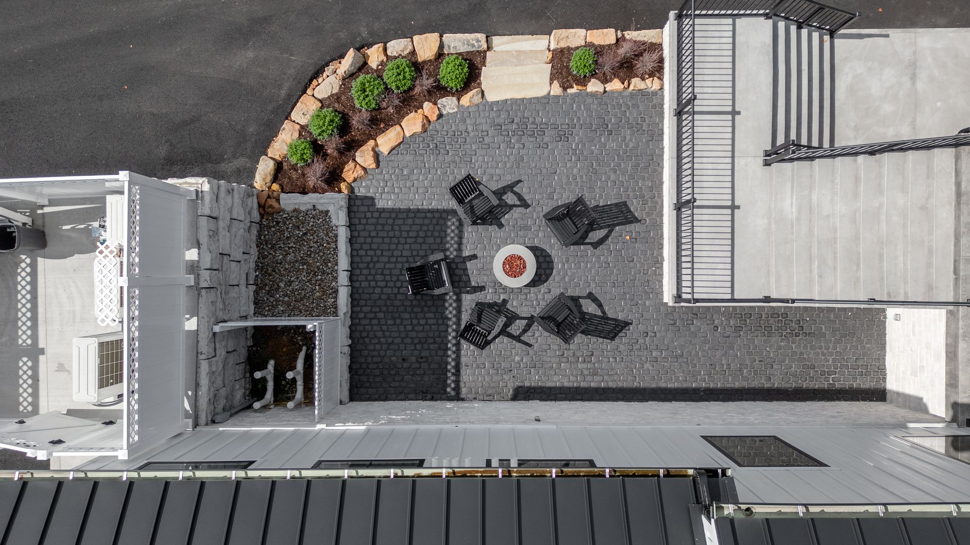 Overhead view of a rooftop patio with tables, chairs, planters, and surrounding building rooftops.