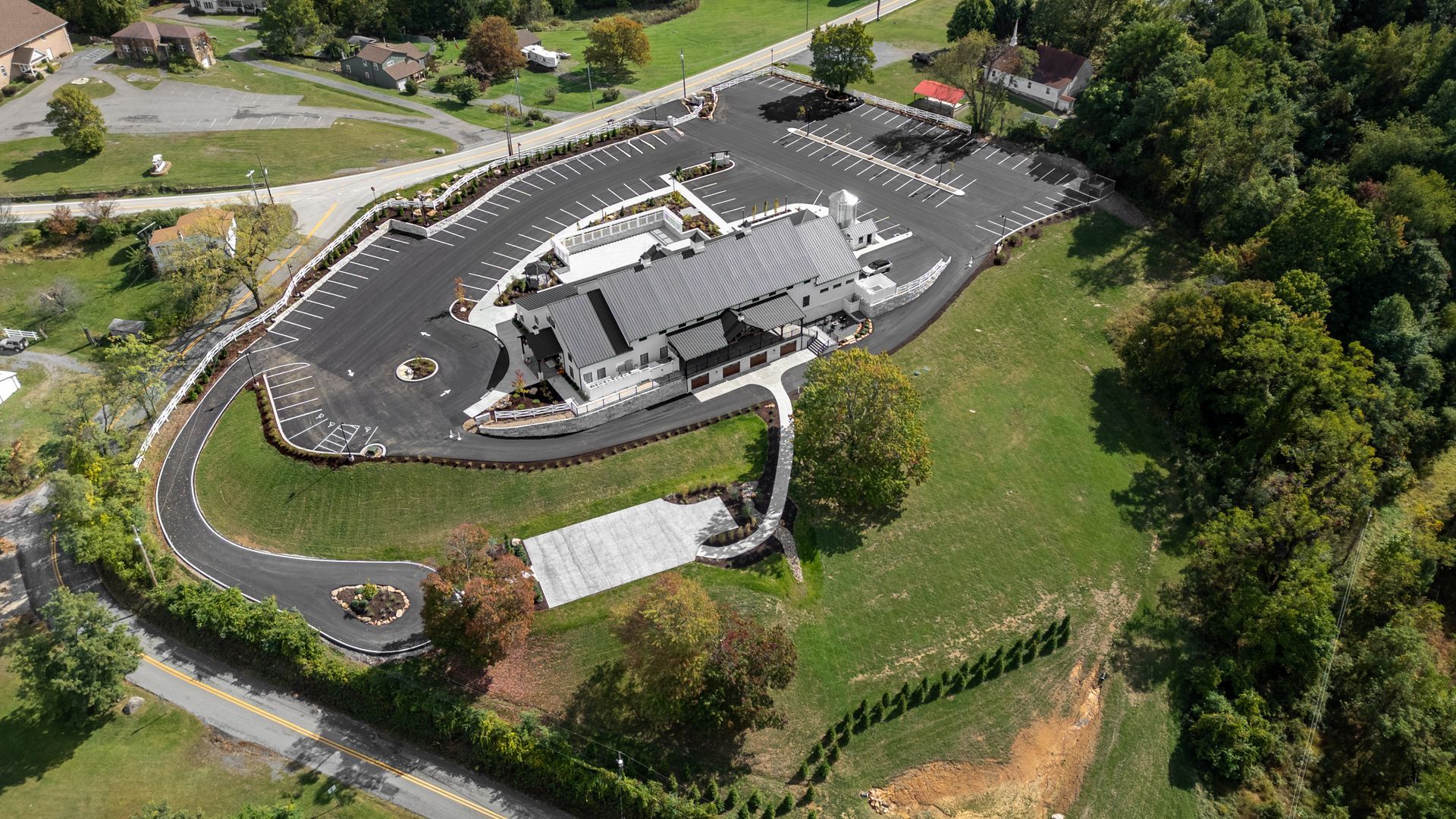 Aerial view of a modern building with a curved driveway and surrounding trees and greenery