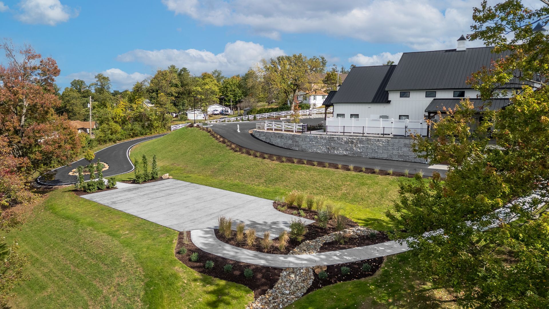 Curving walkway through a grassy landscaped park beside buildings under a blue sky