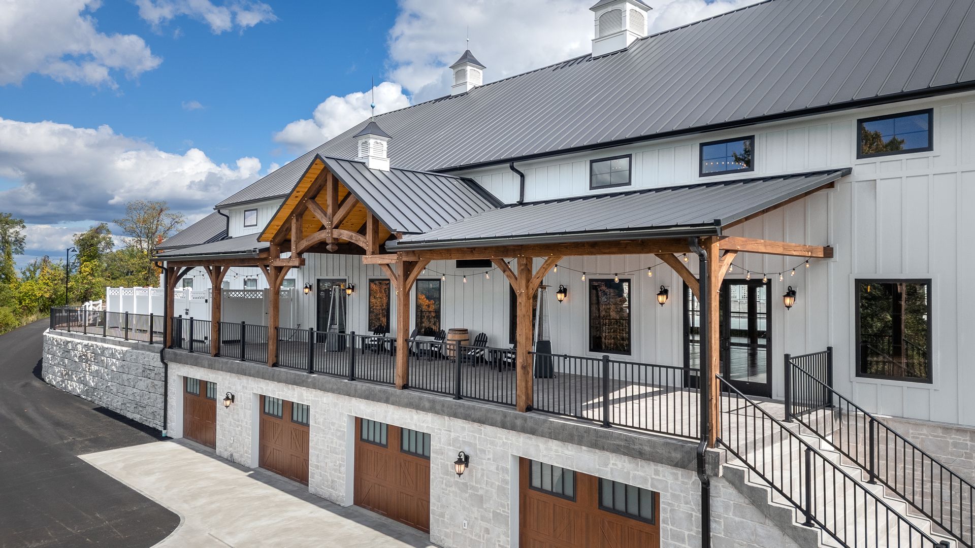 White building with gray roof and wood pergola-covered patio beside a street under a blue sky
