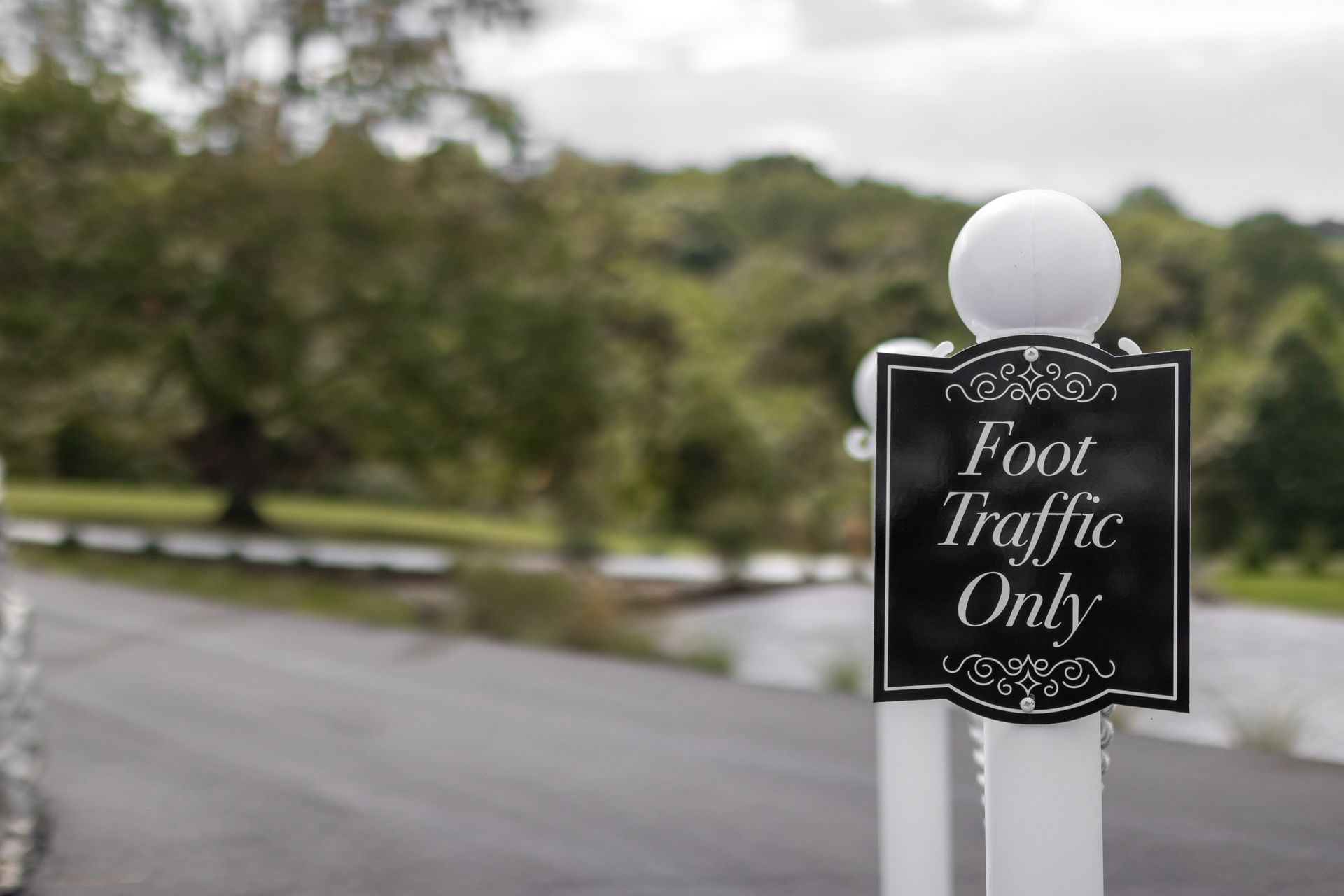 Black sign reading “Food Traffic Only” on a white post beside a road