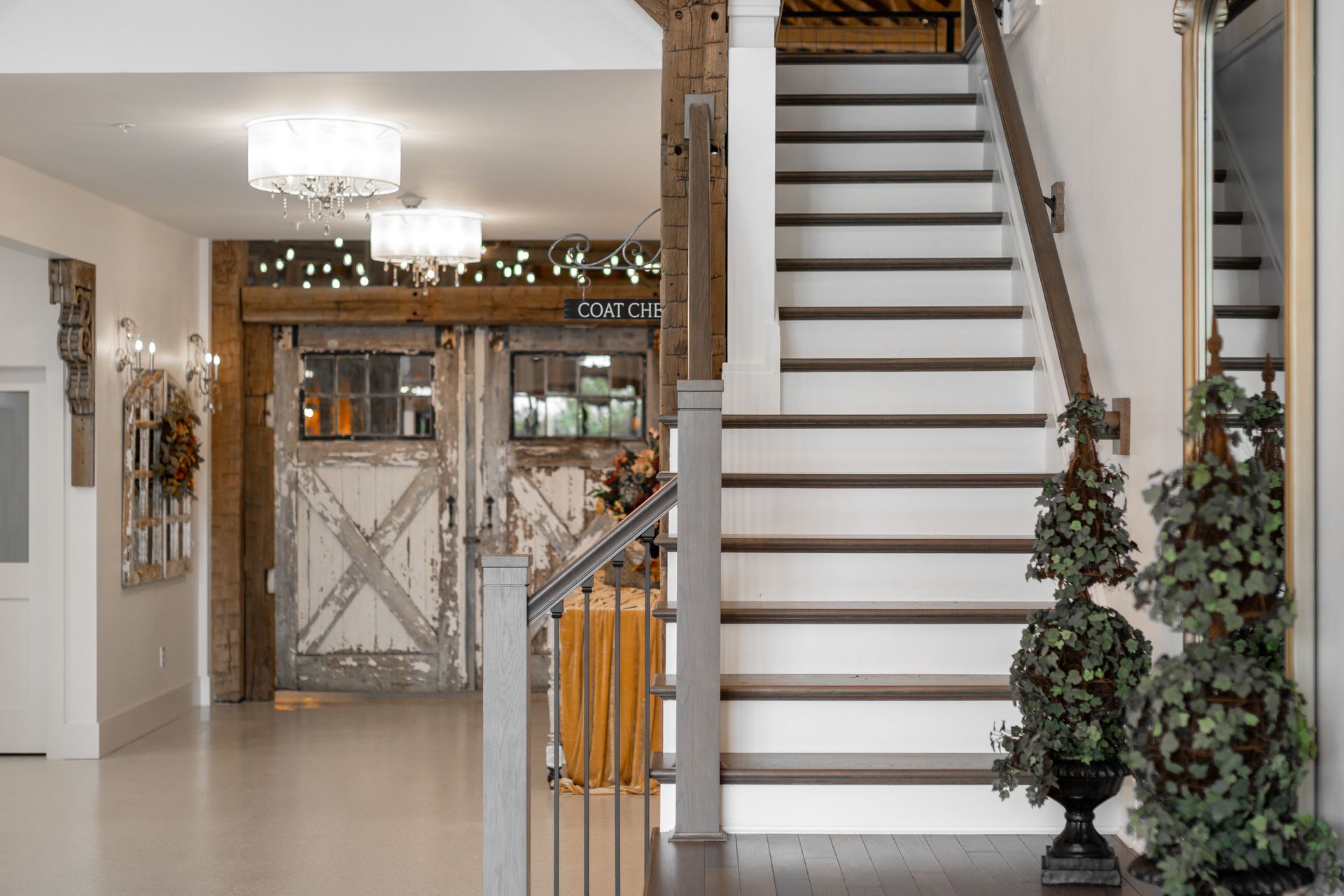 Bright foyer with staircase, chandelier, and rustic barn-style door decoration