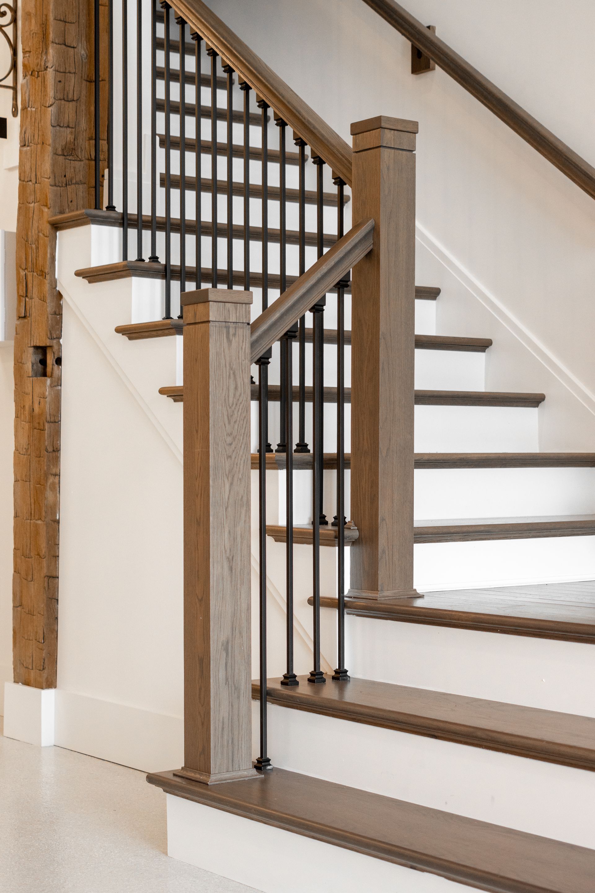 Wooden staircase with black balusters and brown handrails in a home interior
