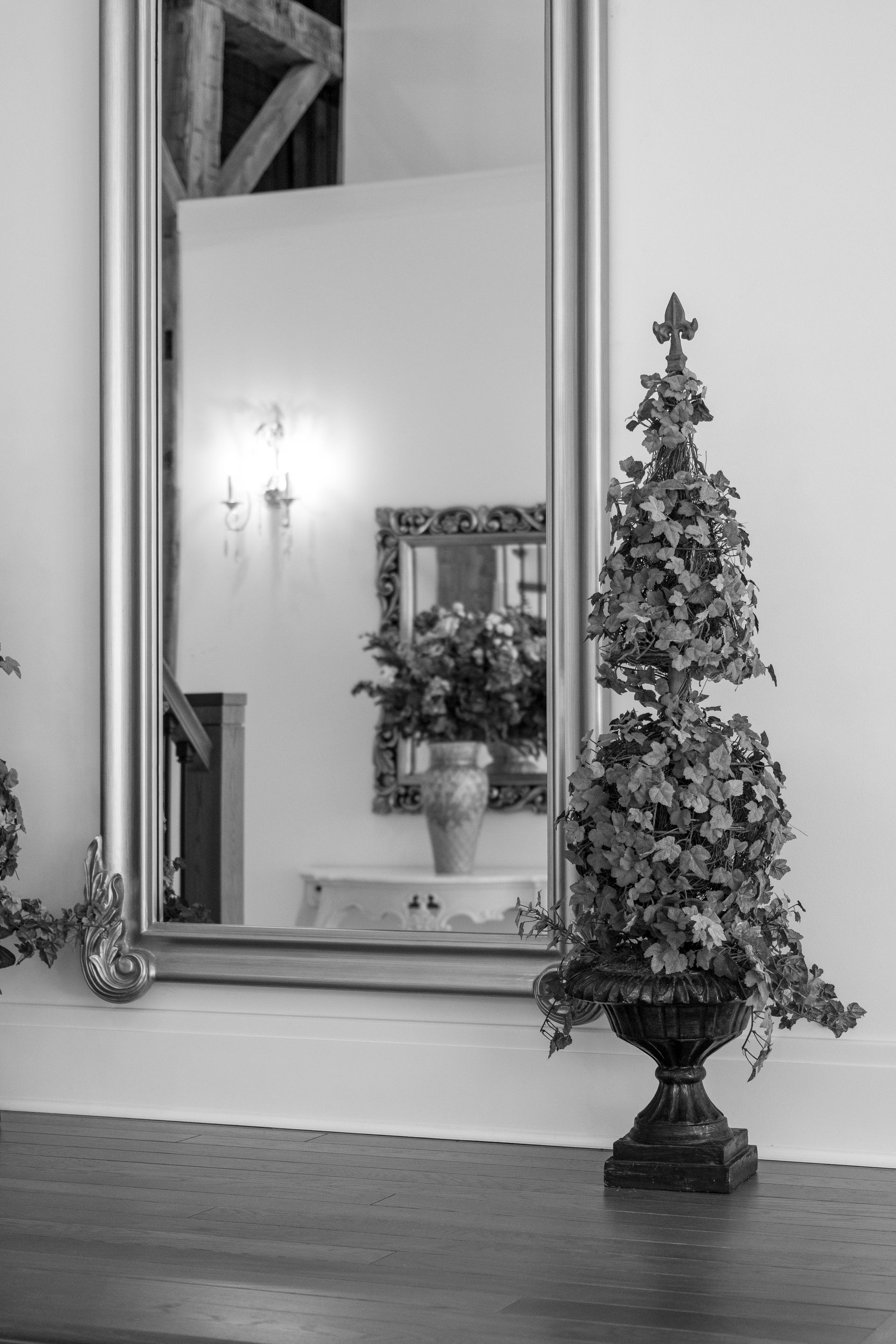 Black-and-white photo of a decorated Christmas tree beside a large wall mirror in a room