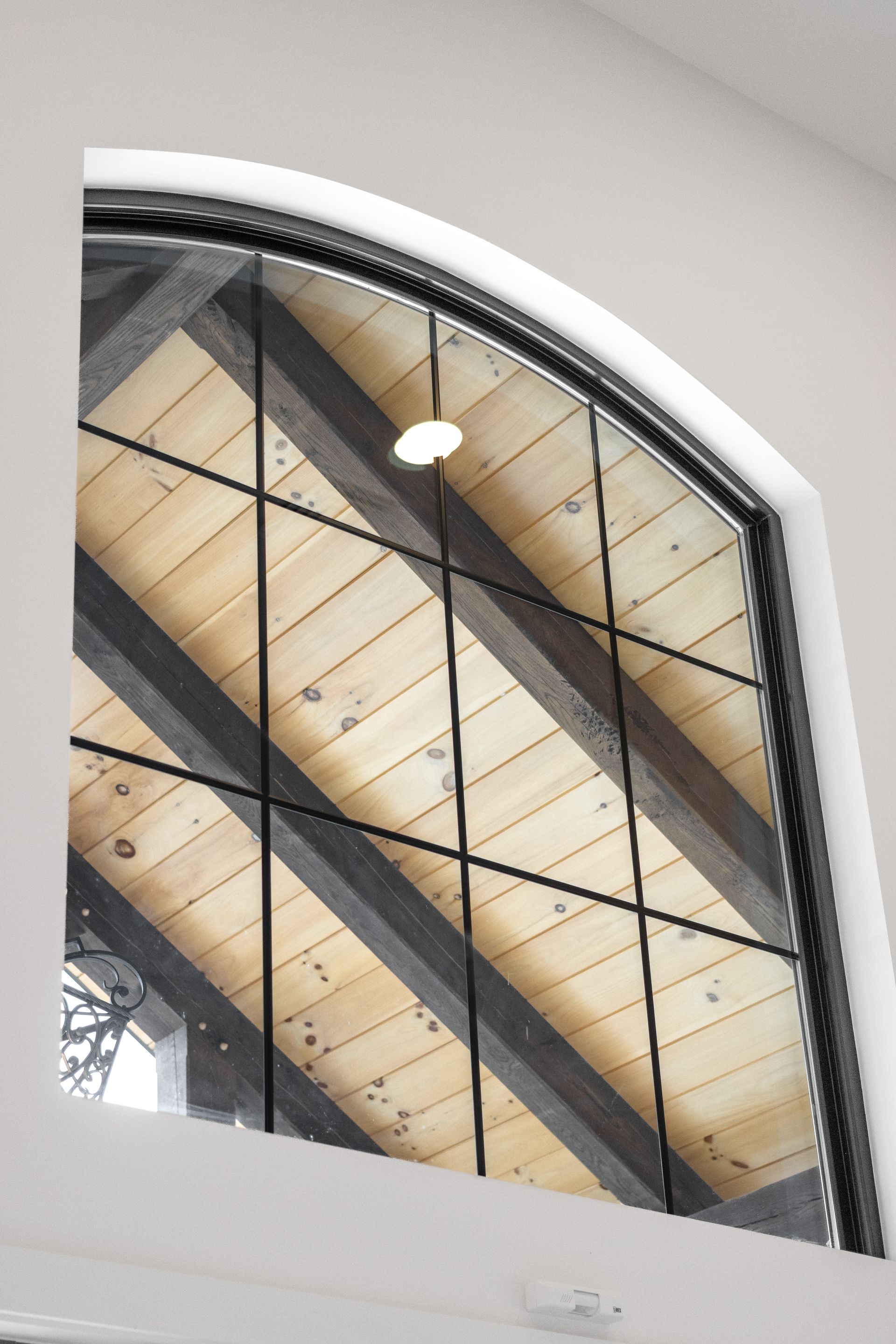 Arched industrial window with black metal framework and a hanging light inside