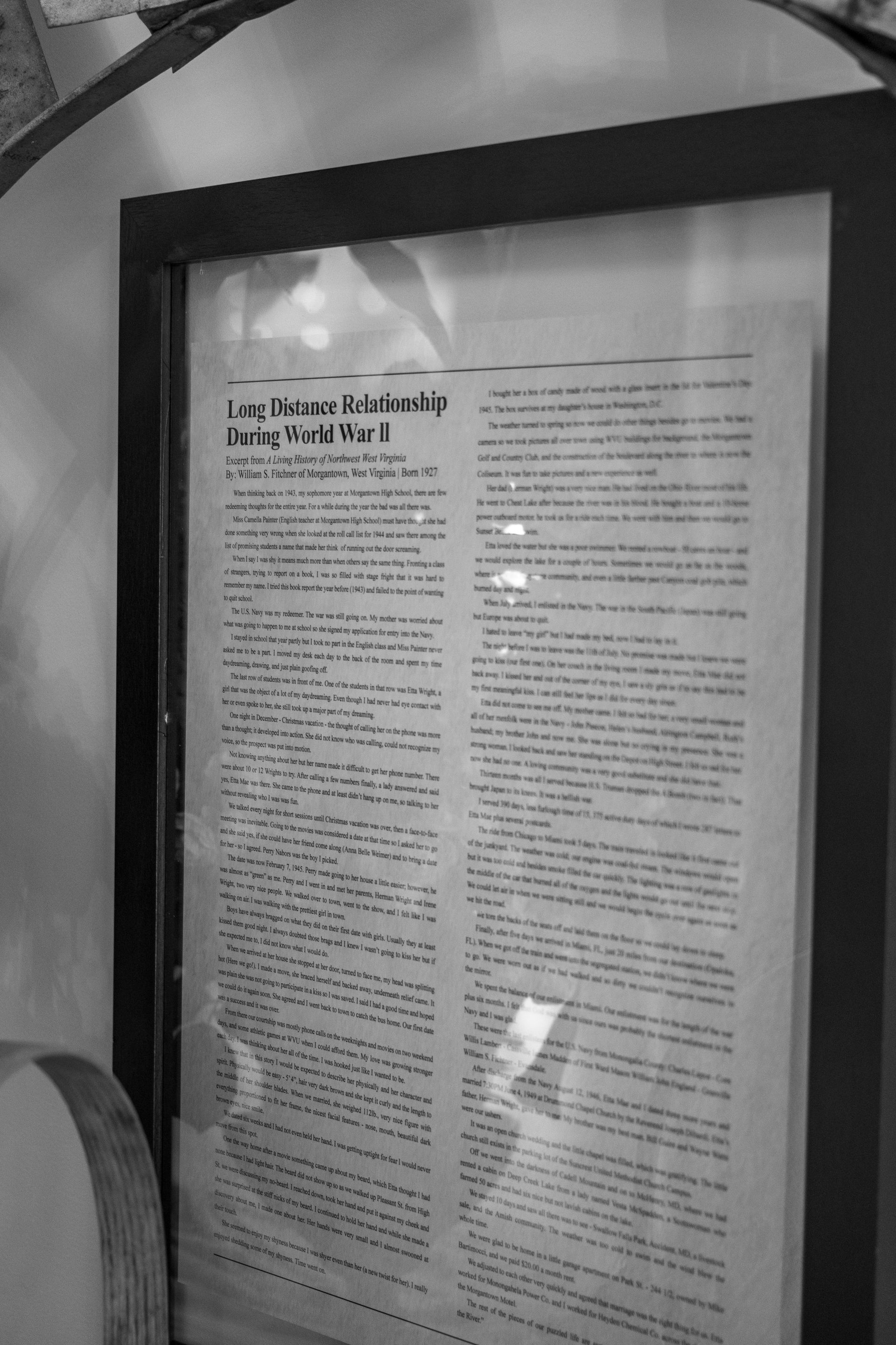 Framed newspaper page on a wall, shown in black and white.