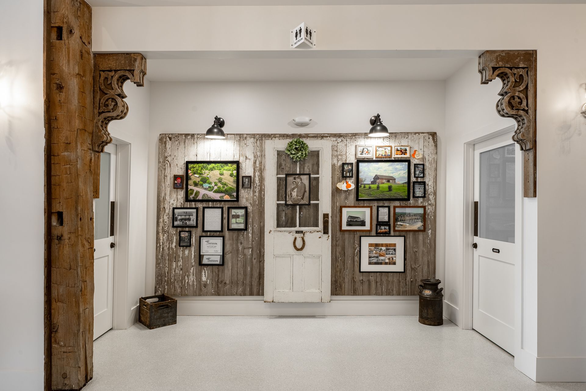 Art gallery hallway with framed artwork, white walls, and decorative wooden beams