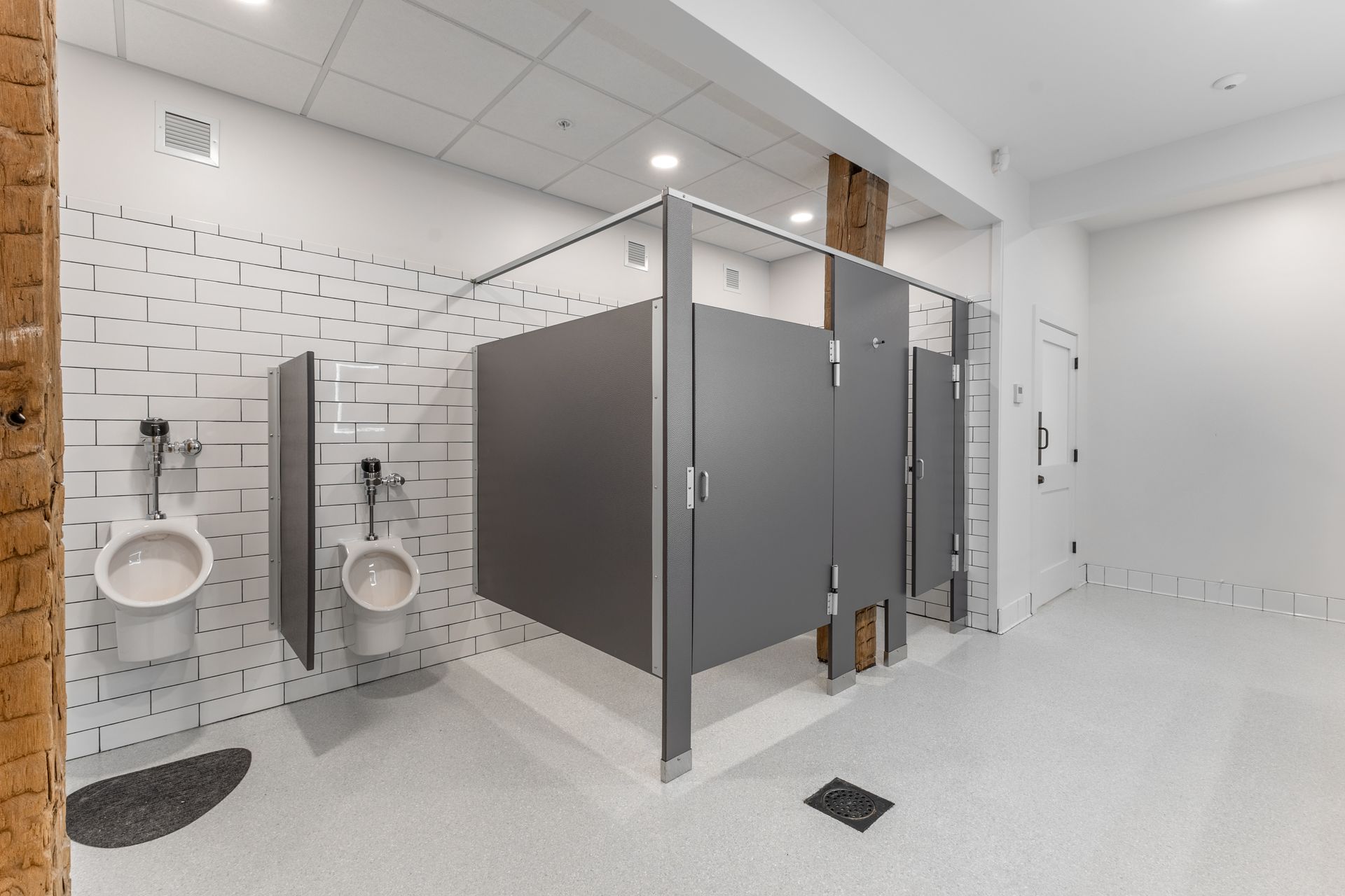 White Oak 1838's restroom with gray stall partitions, white tiled walls, and urinals on the left.