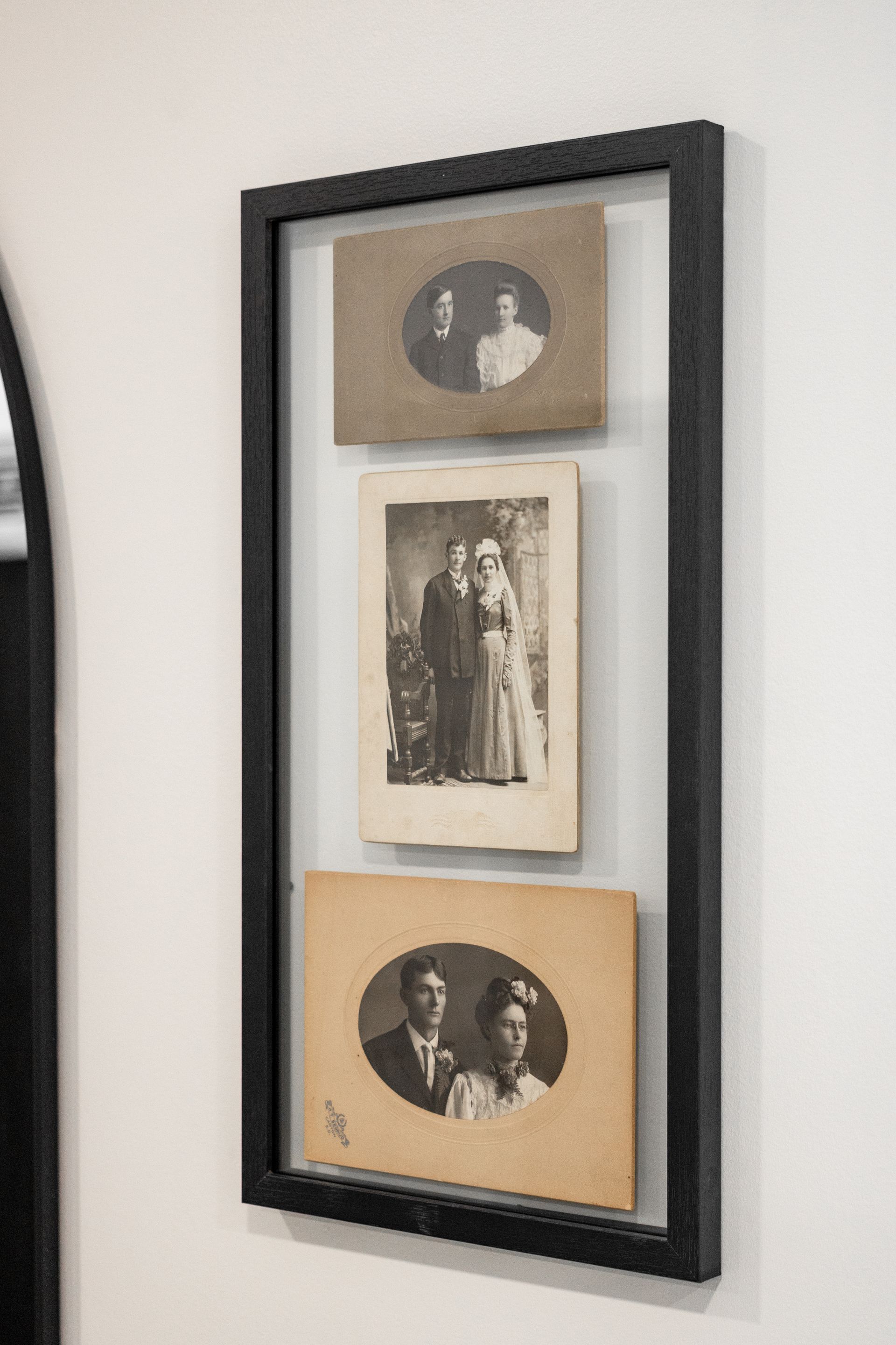 Framed vertical collage of three vintage sepia photos in a black frame on a light wall