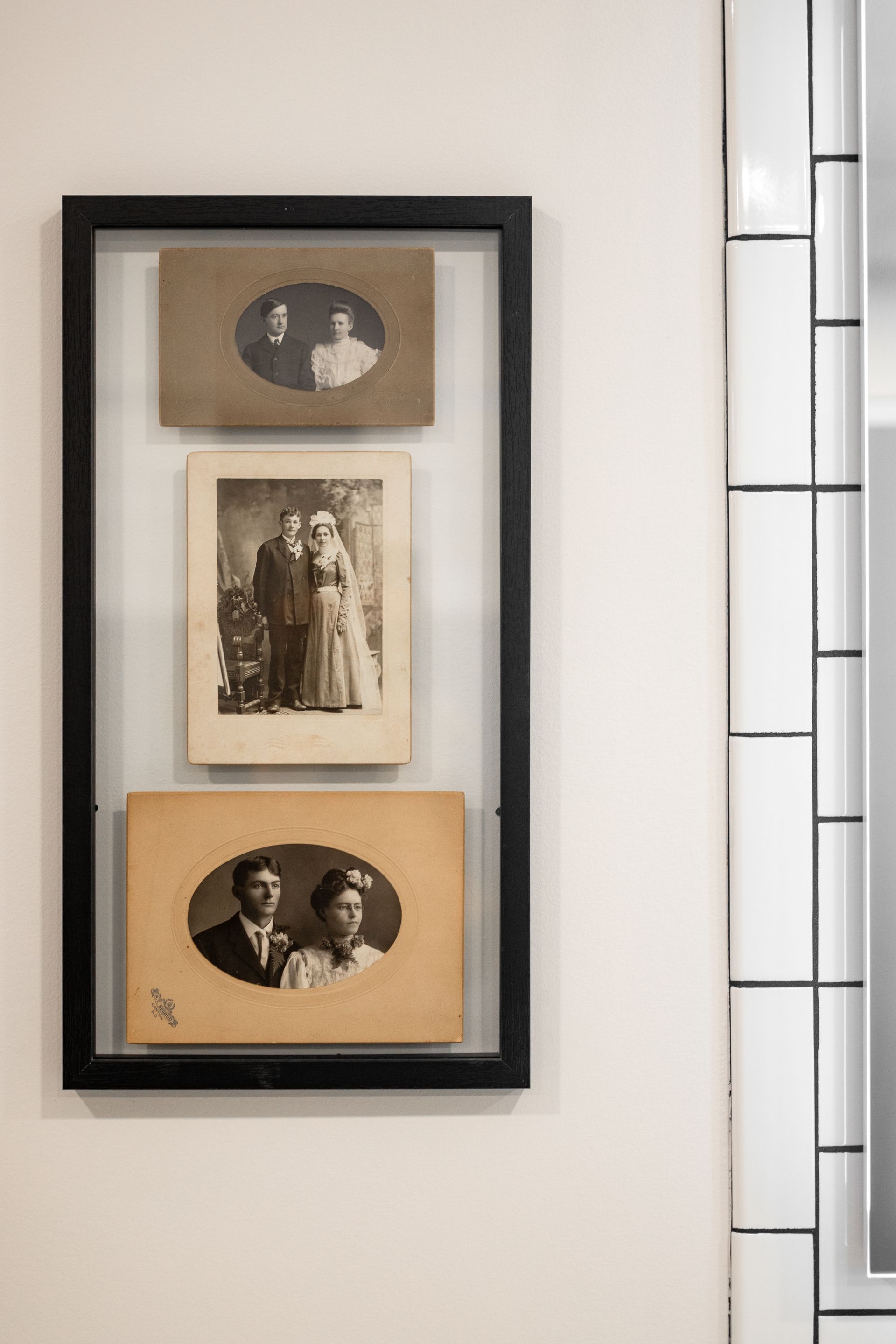 Framed collage of three vintage sepia photographs on a wall beside a window.