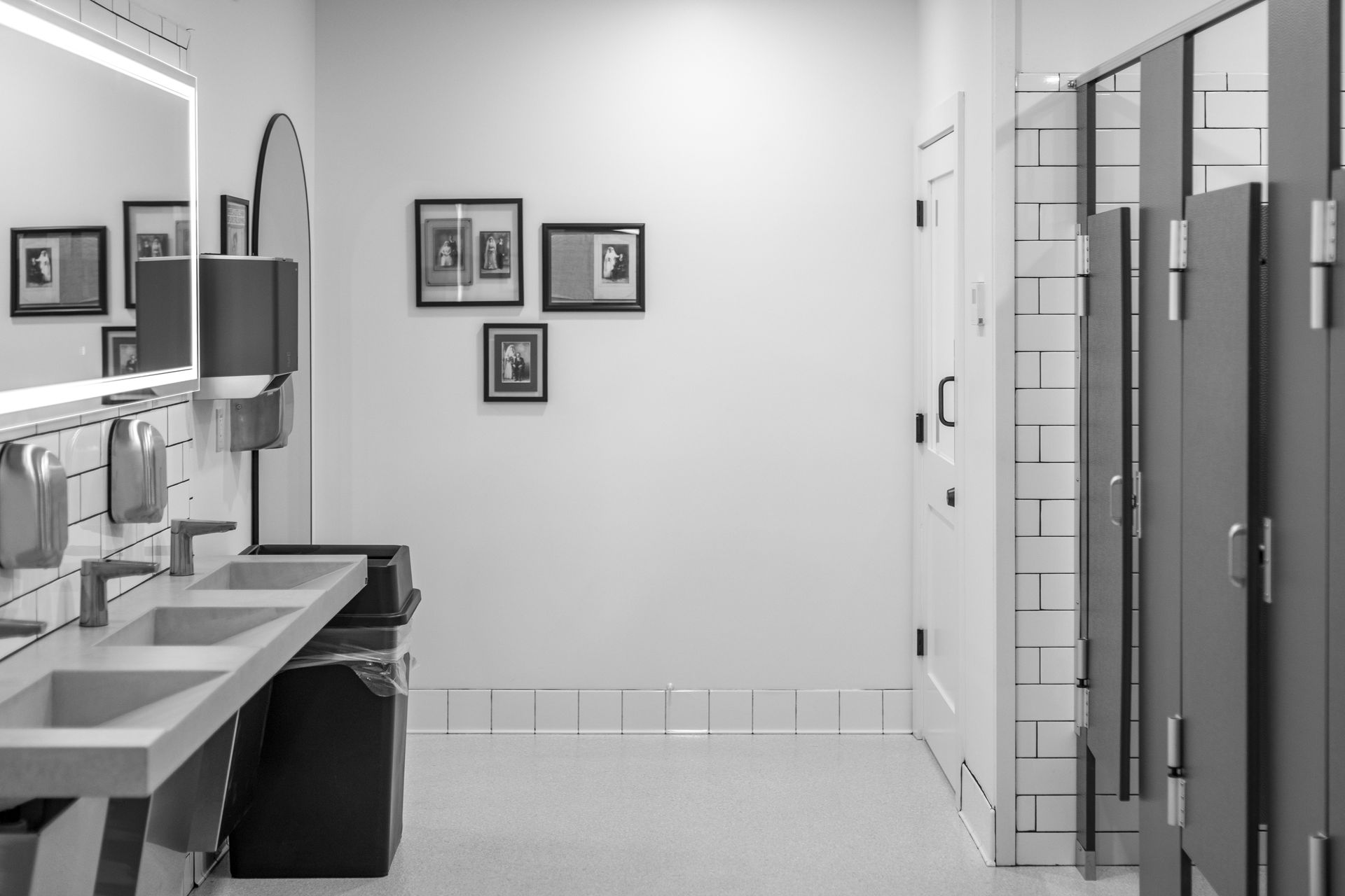 Modern bathroom with sinks, mirror, wall art, and shower stalls along the right side.