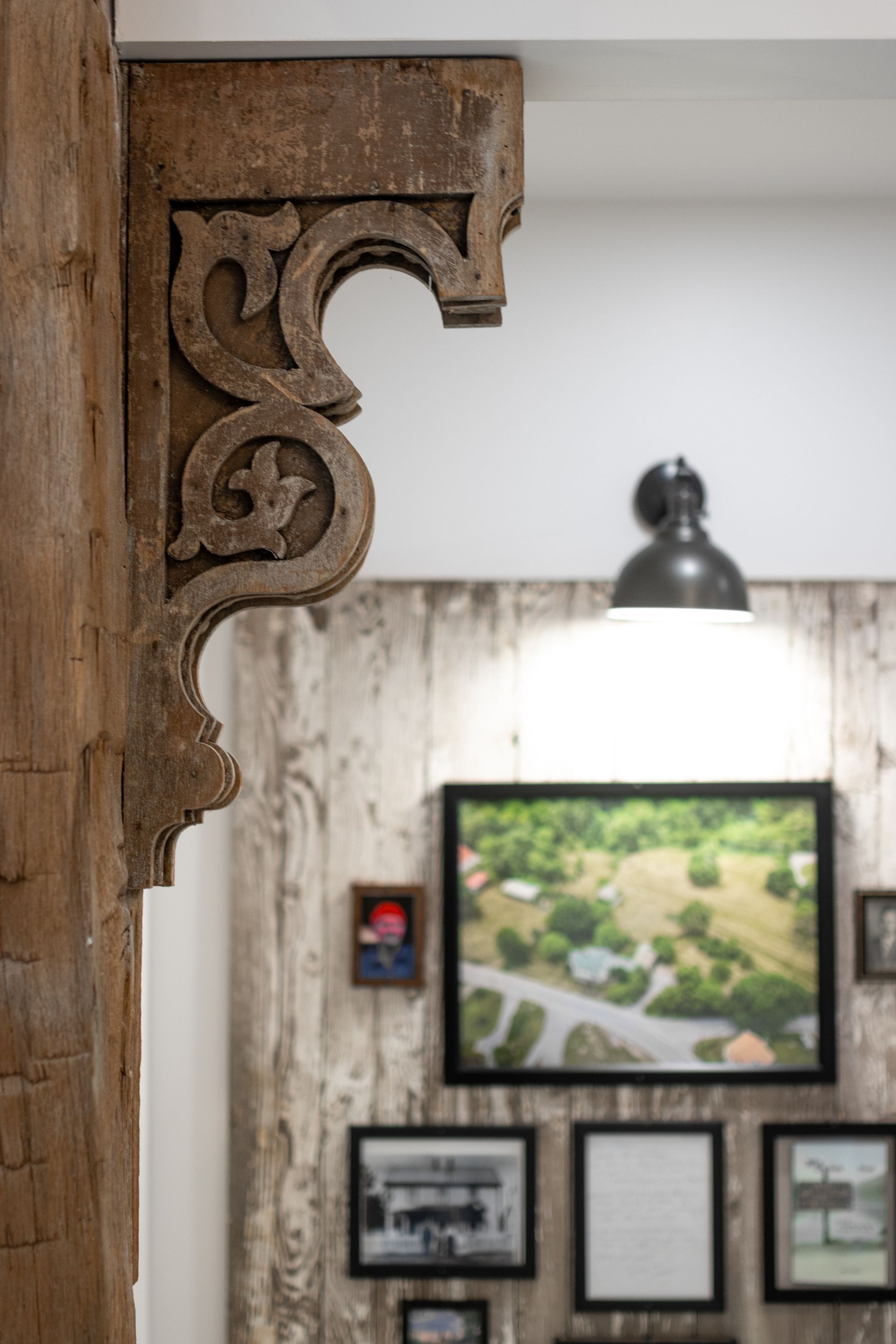 Ornate wooden post framing a gallery wall with framed art and a hanging lamp