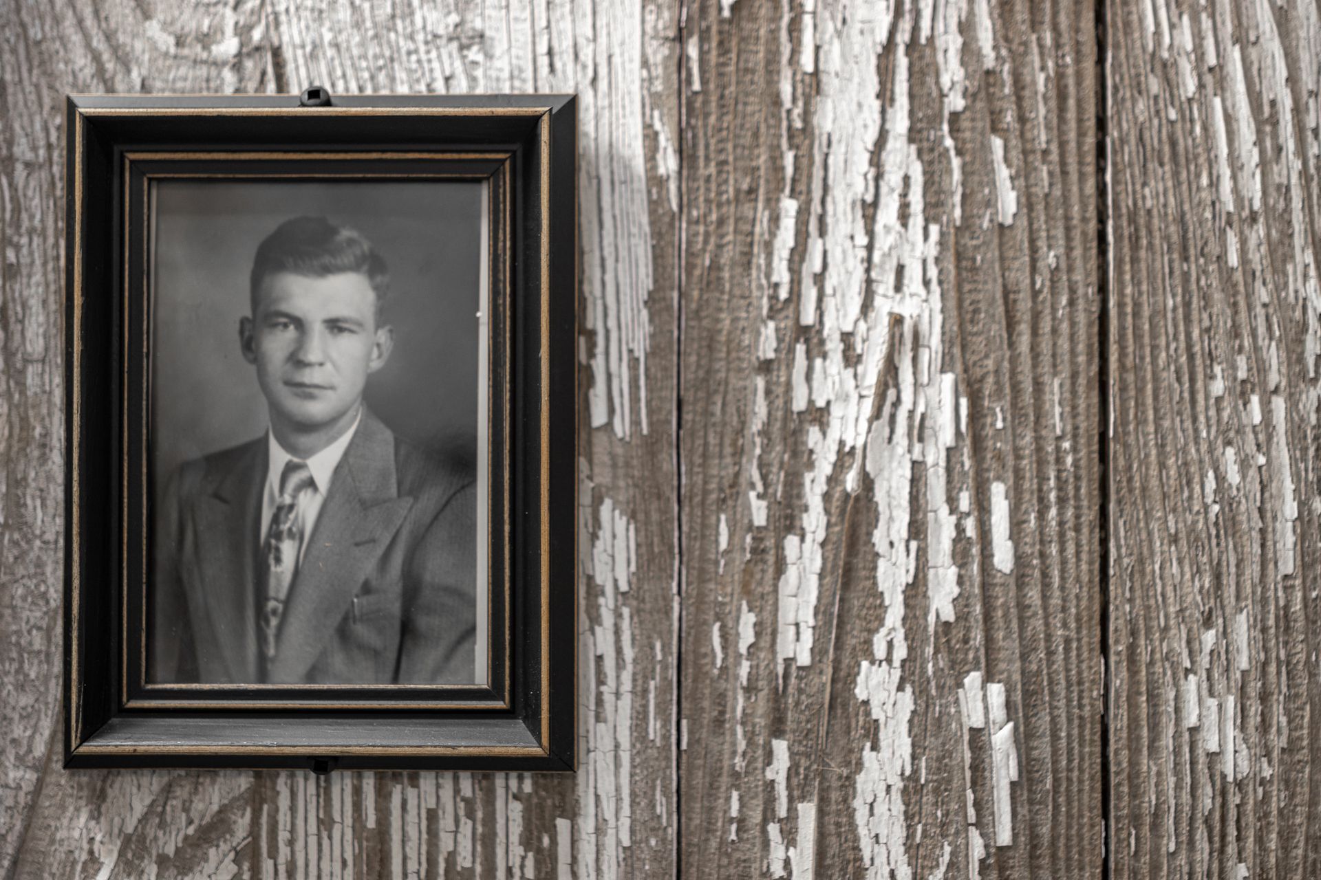Framed black-and-white portrait on weathered wooden wall