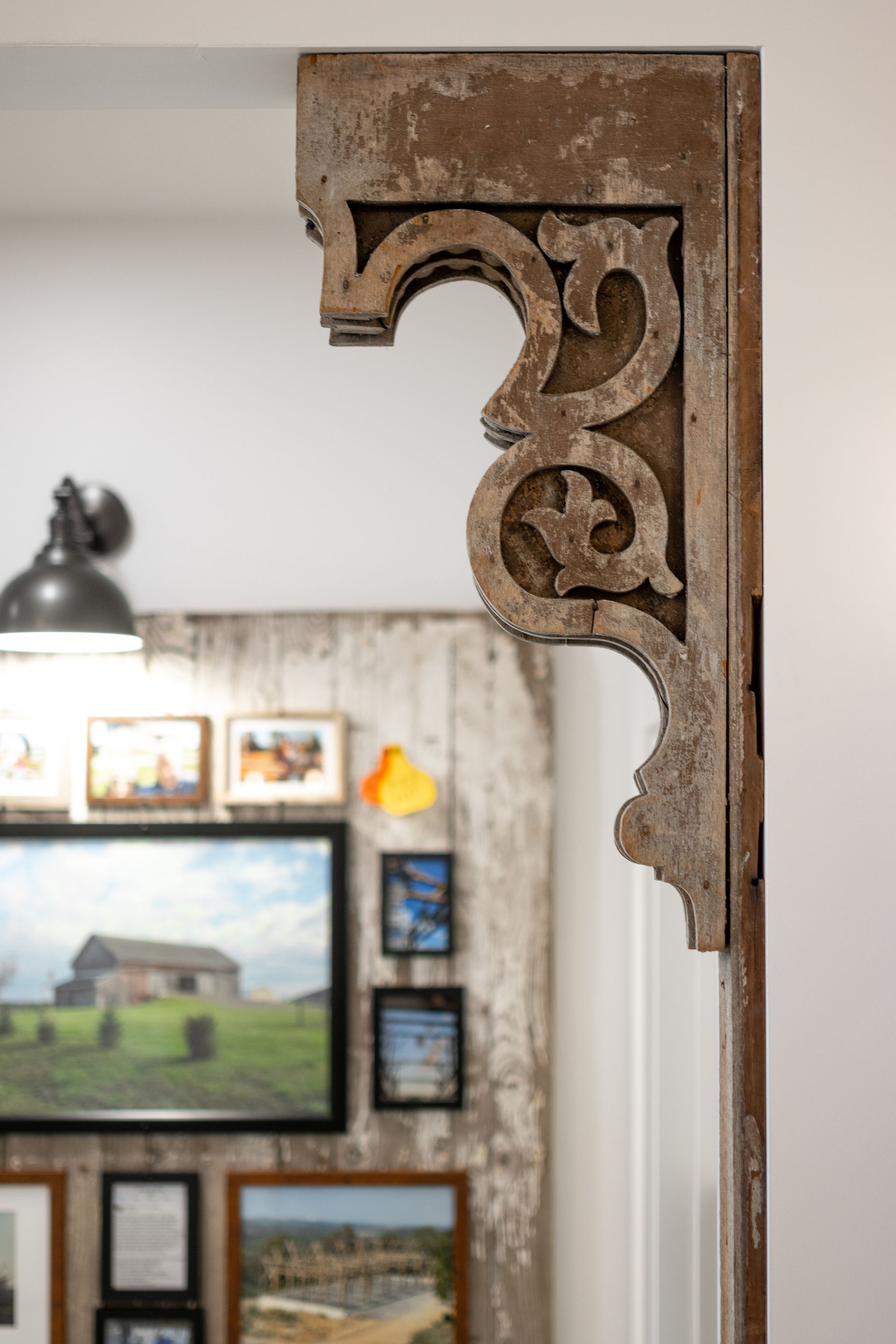 Rusty ornate carved bracket on a white interior wall in a gallery-like room